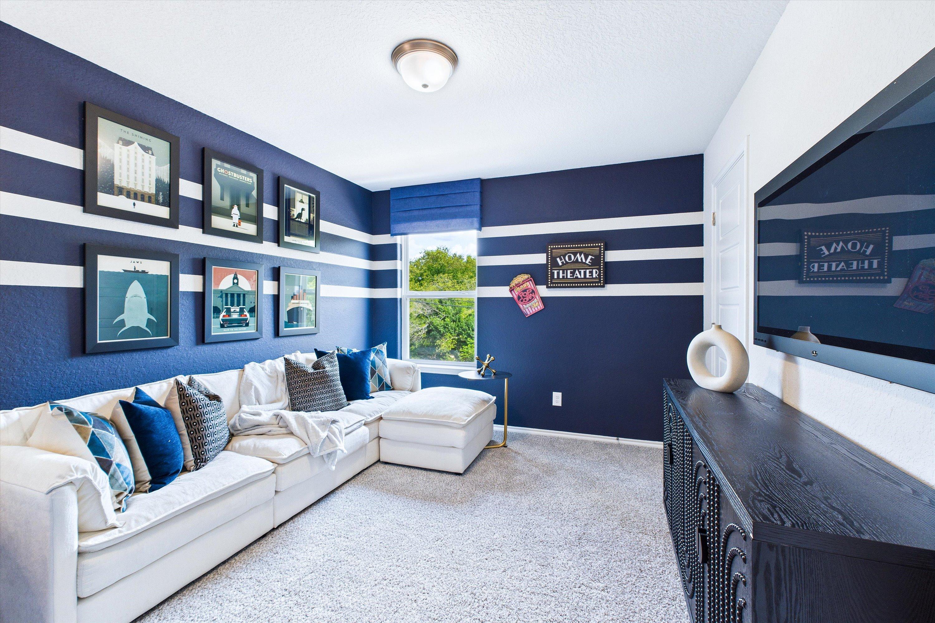 Navy blue striped game room at Cedar Heights in San Antonio TX with white L-shaped sectional, wall TV, and framed art