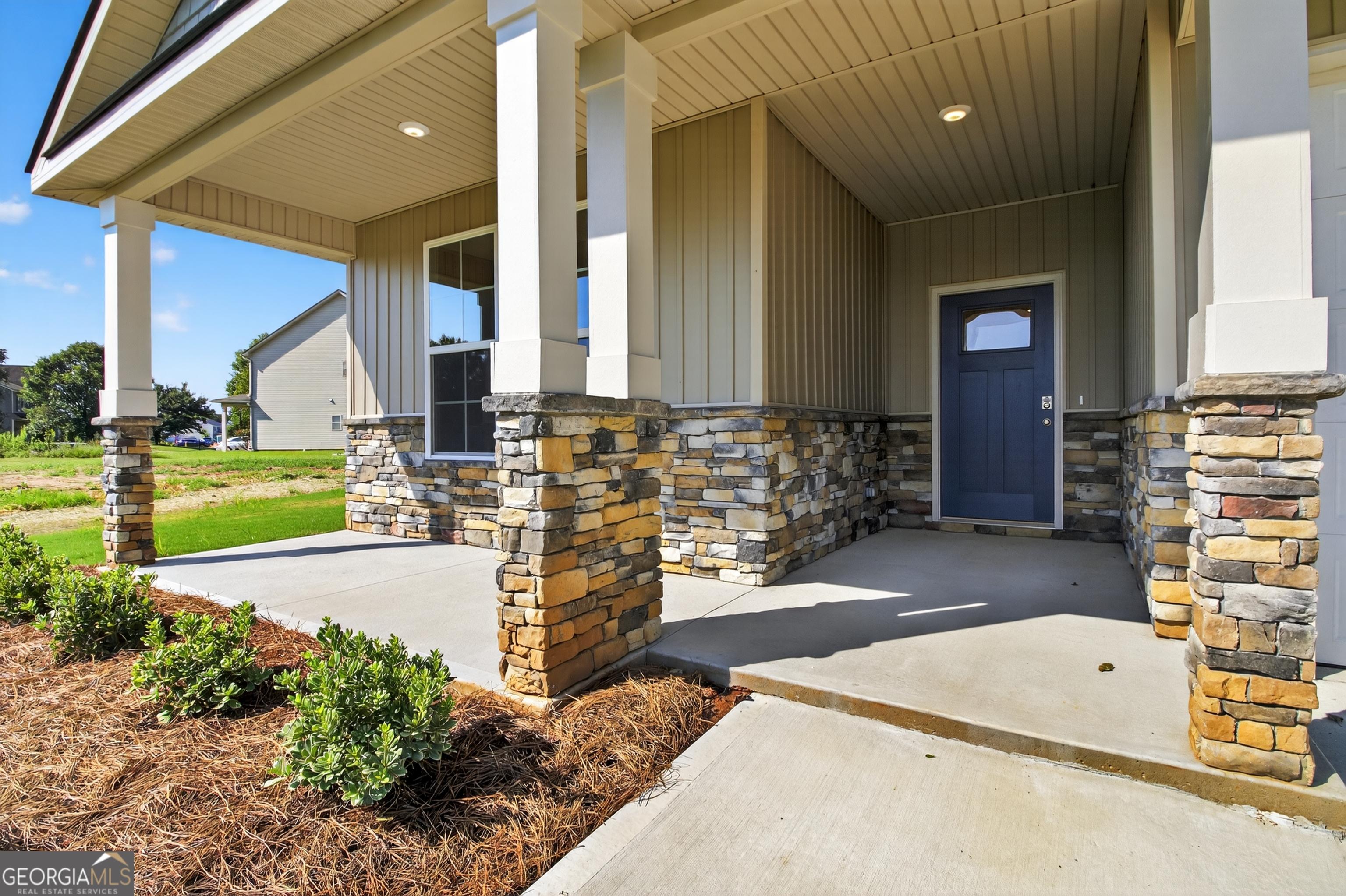 Charming front porch with stone pillars and navy blue door on The Luna 4-bedroom home by Evermore Homes in Ivy Glen, Perry, Georgia