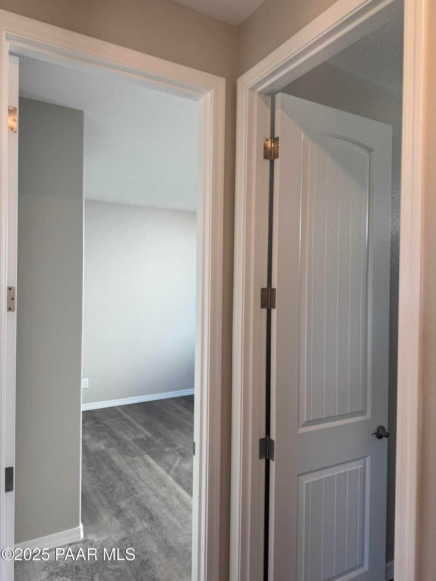 Hallway with open white doors and gray luxury vinyl flooring in 3-bedroom Davidson Homes The Monarch E, Prescott AZ