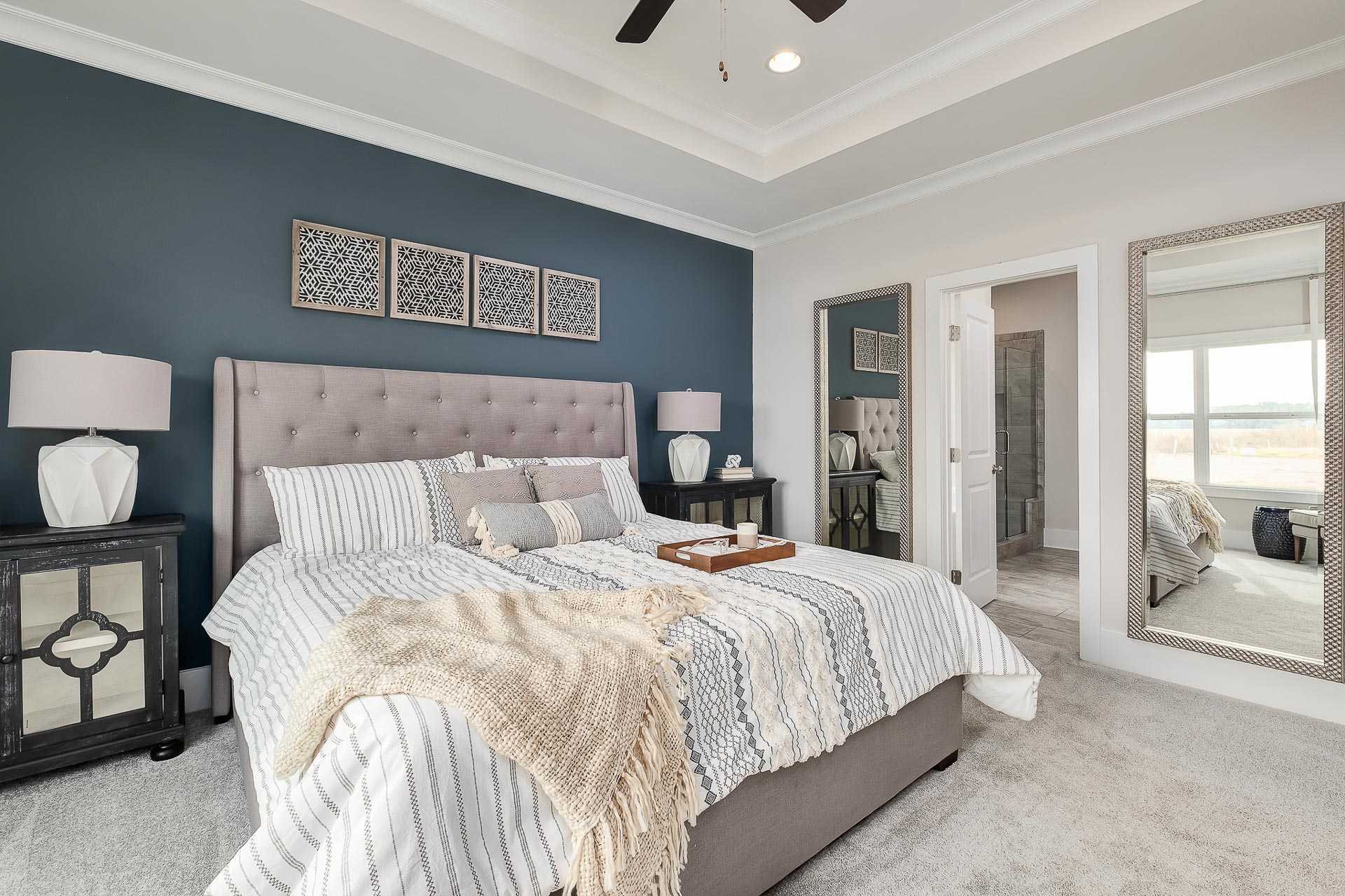 owner's suite with blue accent wall and light bedding at The Reserve at North Ridge by Davidson Homes