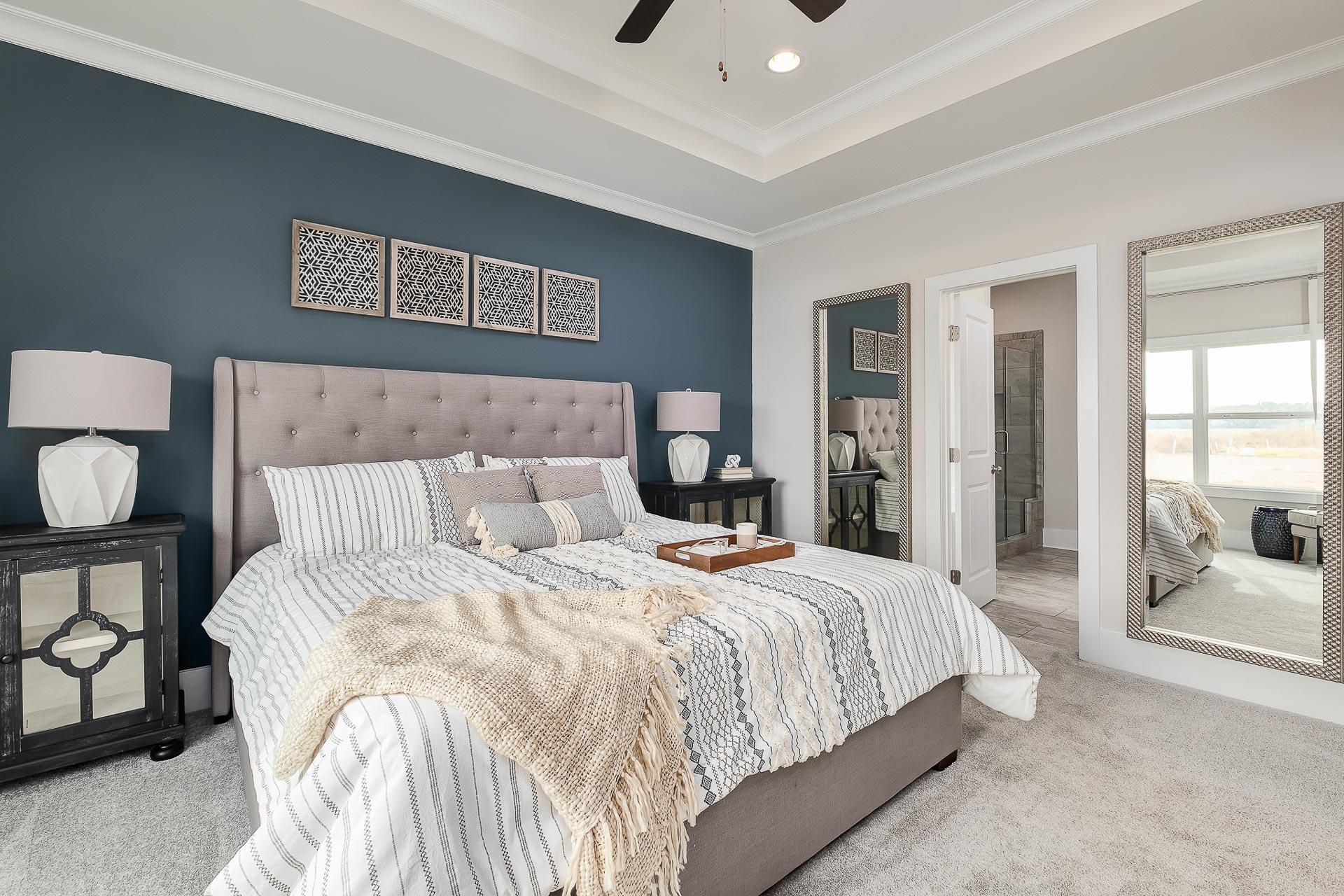 owner's suite with blue accent wall and light bedding at The Reserve at North Ridge by Davidson Homes