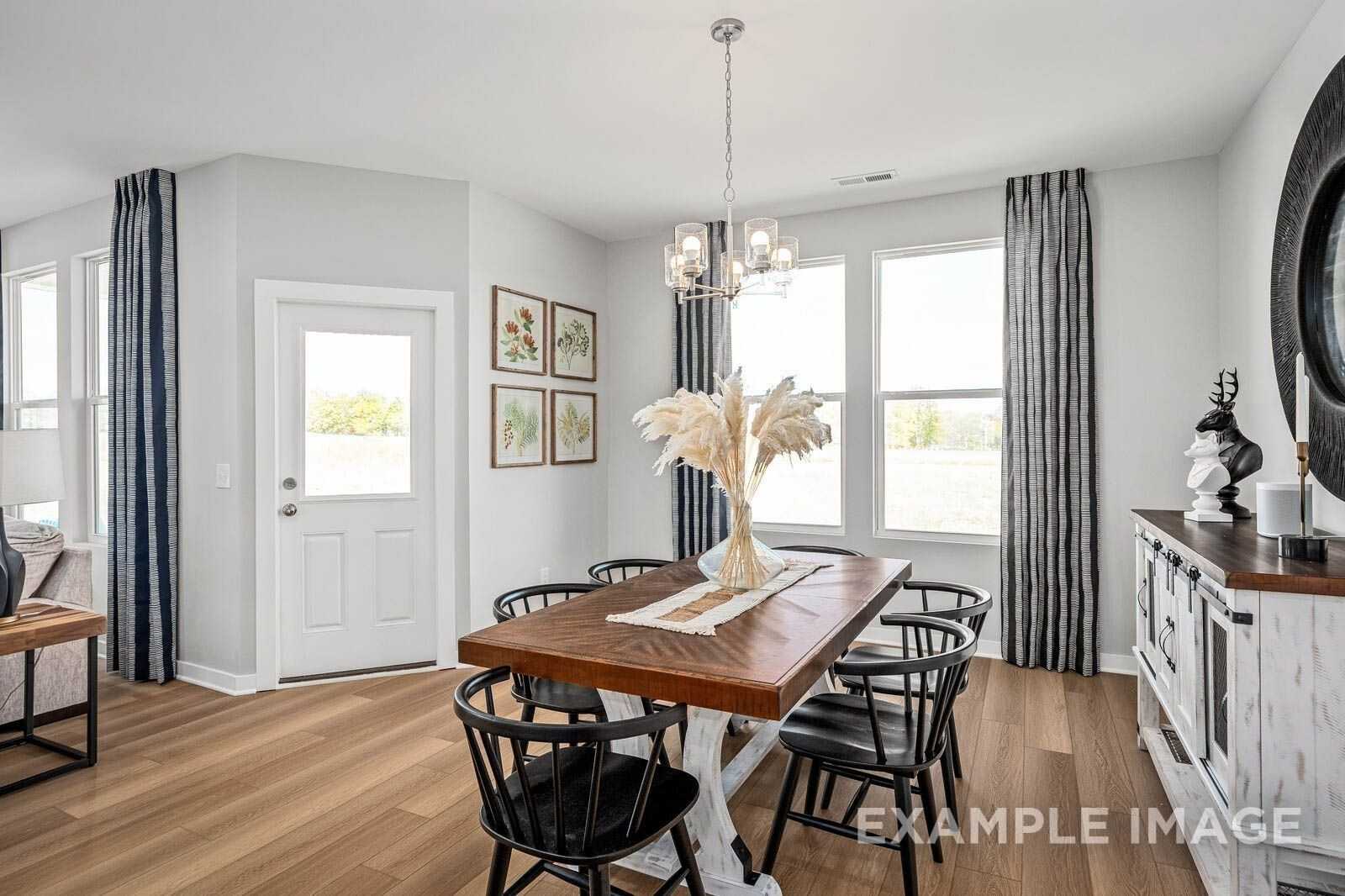 Elegant dining room with farmhouse table, black chairs, chandelier, and French doors in The Franklin B by Davidson Homes, White House, TN