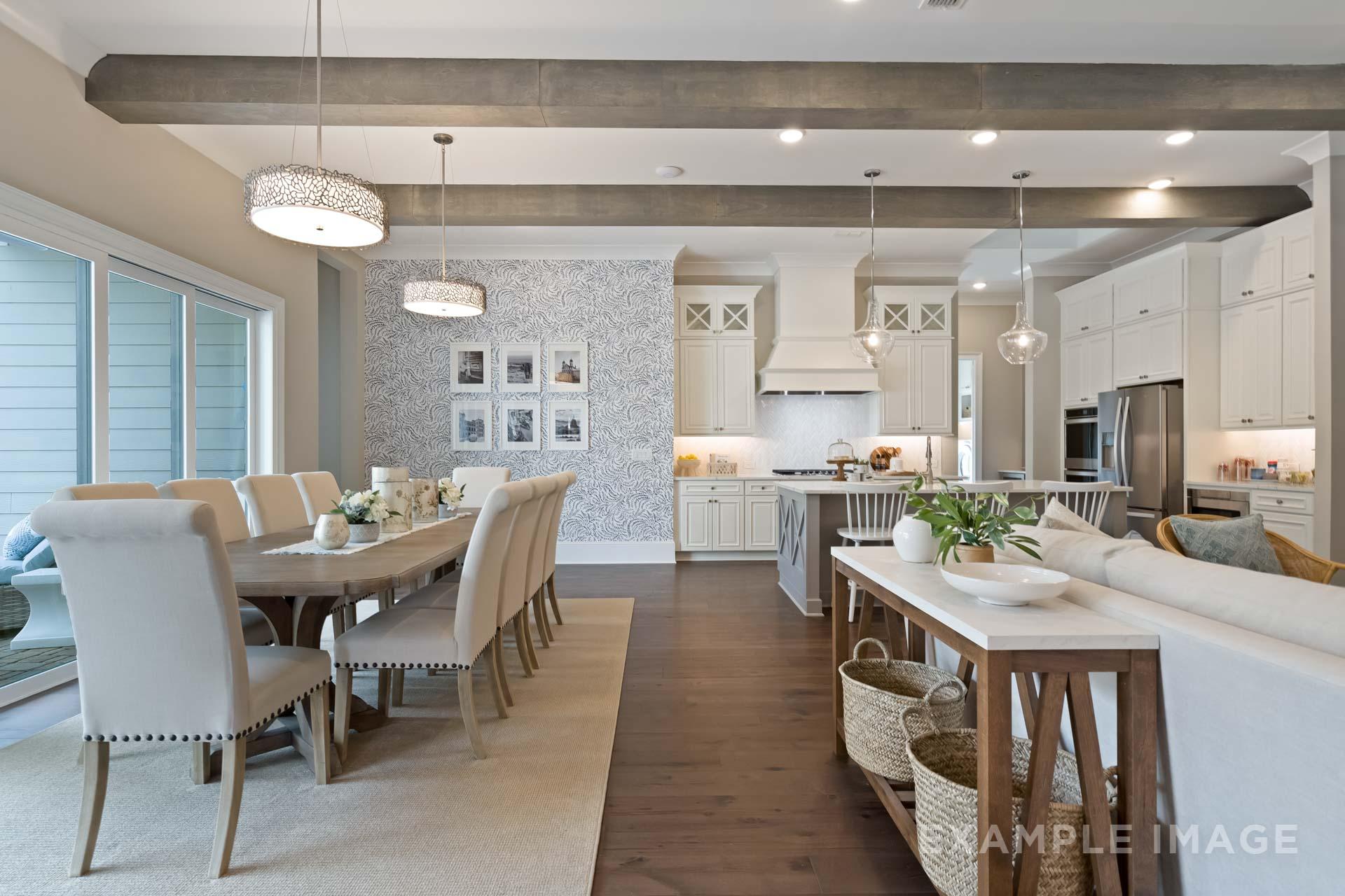 Open-concept kitchen and dining in The Seaside C with white cabinetry, large island, exposed beams, and hardwood floors