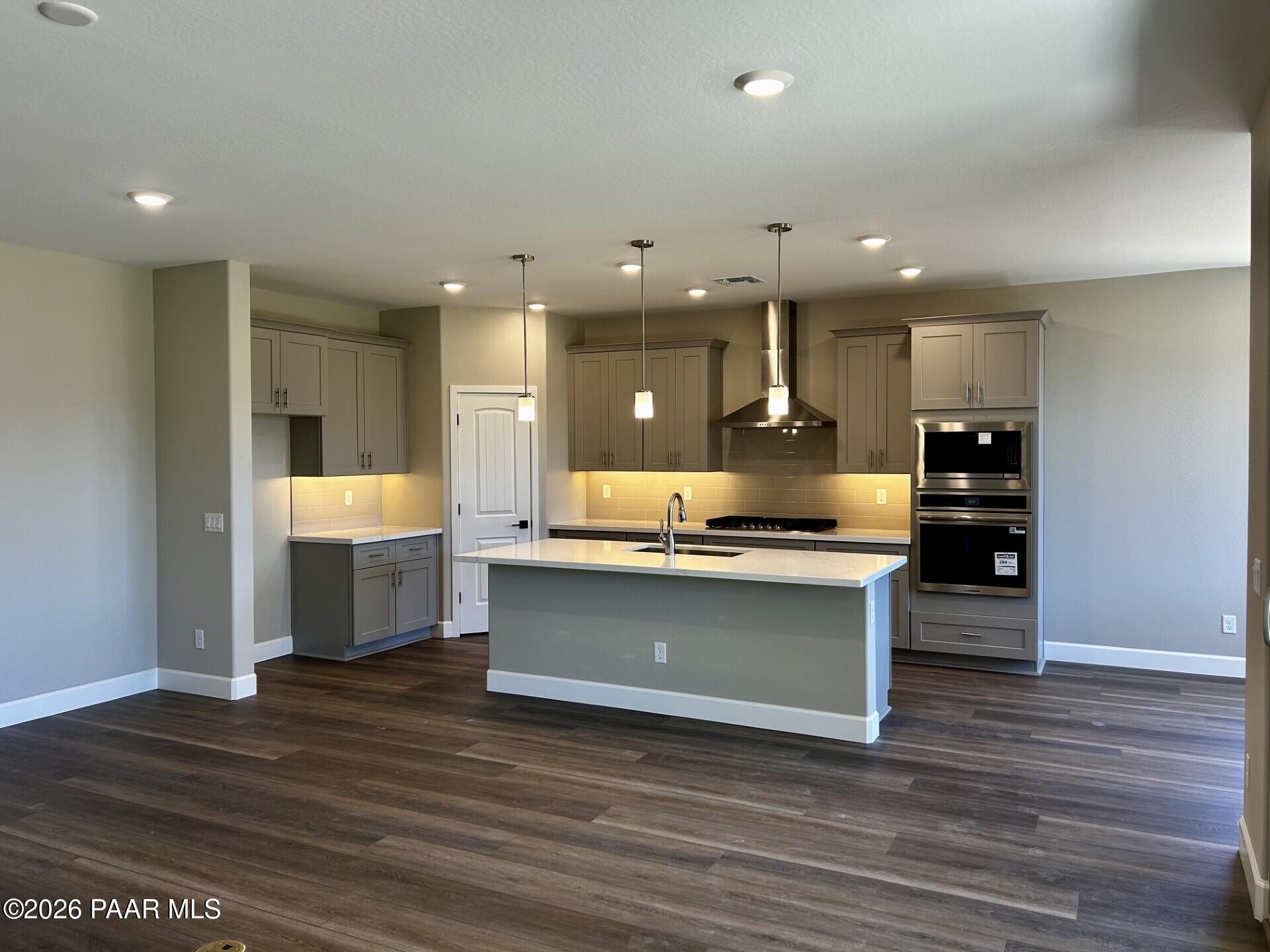 Modern kitchen with center island, gray cabinets, and stainless steel appliances in The Harmony C floor plan, Prescott.