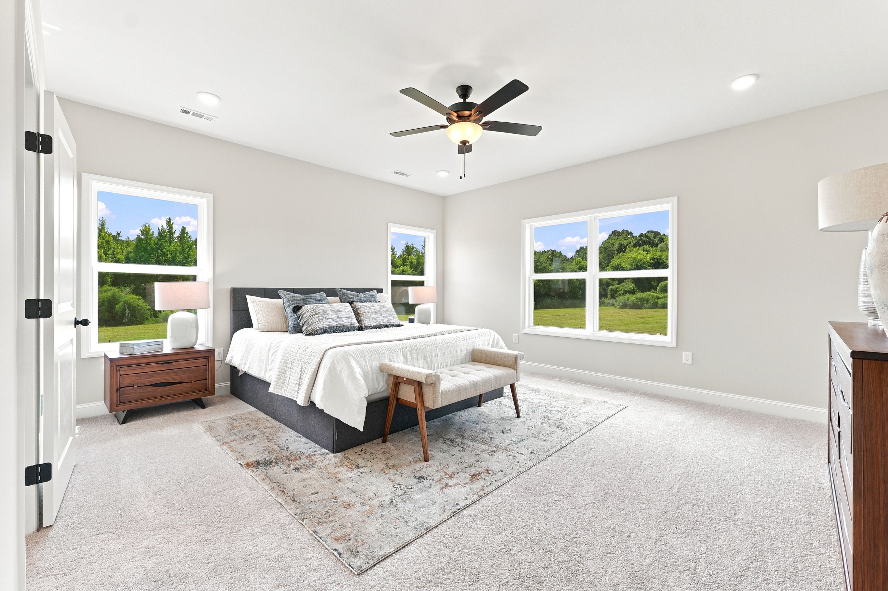 Spacious master bedroom at Riverton Preserve in Huntsville, AL by Davidson Homes with large windows and neutral decor.