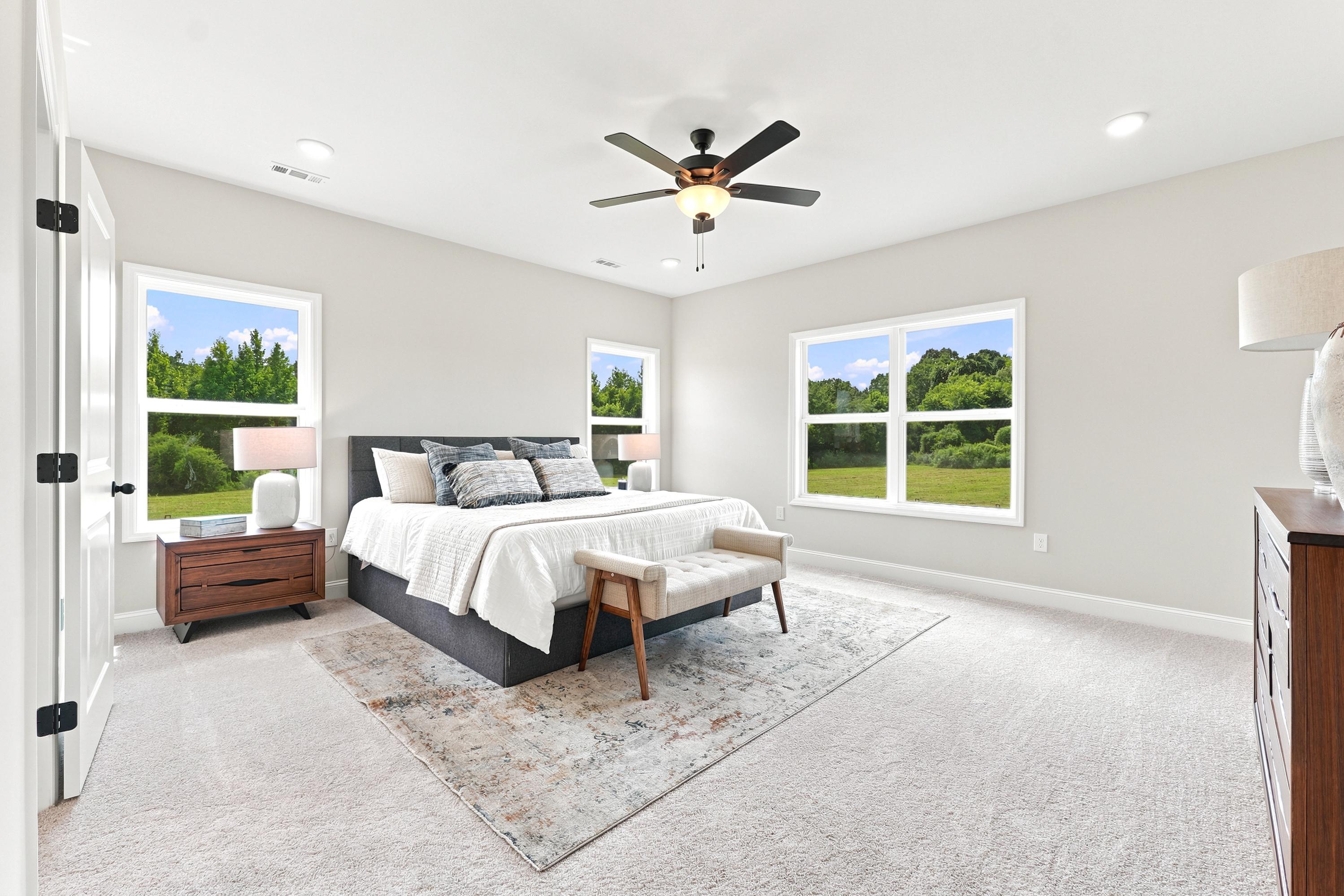 Spacious master bedroom at Riverton Preserve in Huntsville, AL by Davidson Homes with large windows and neutral decor.