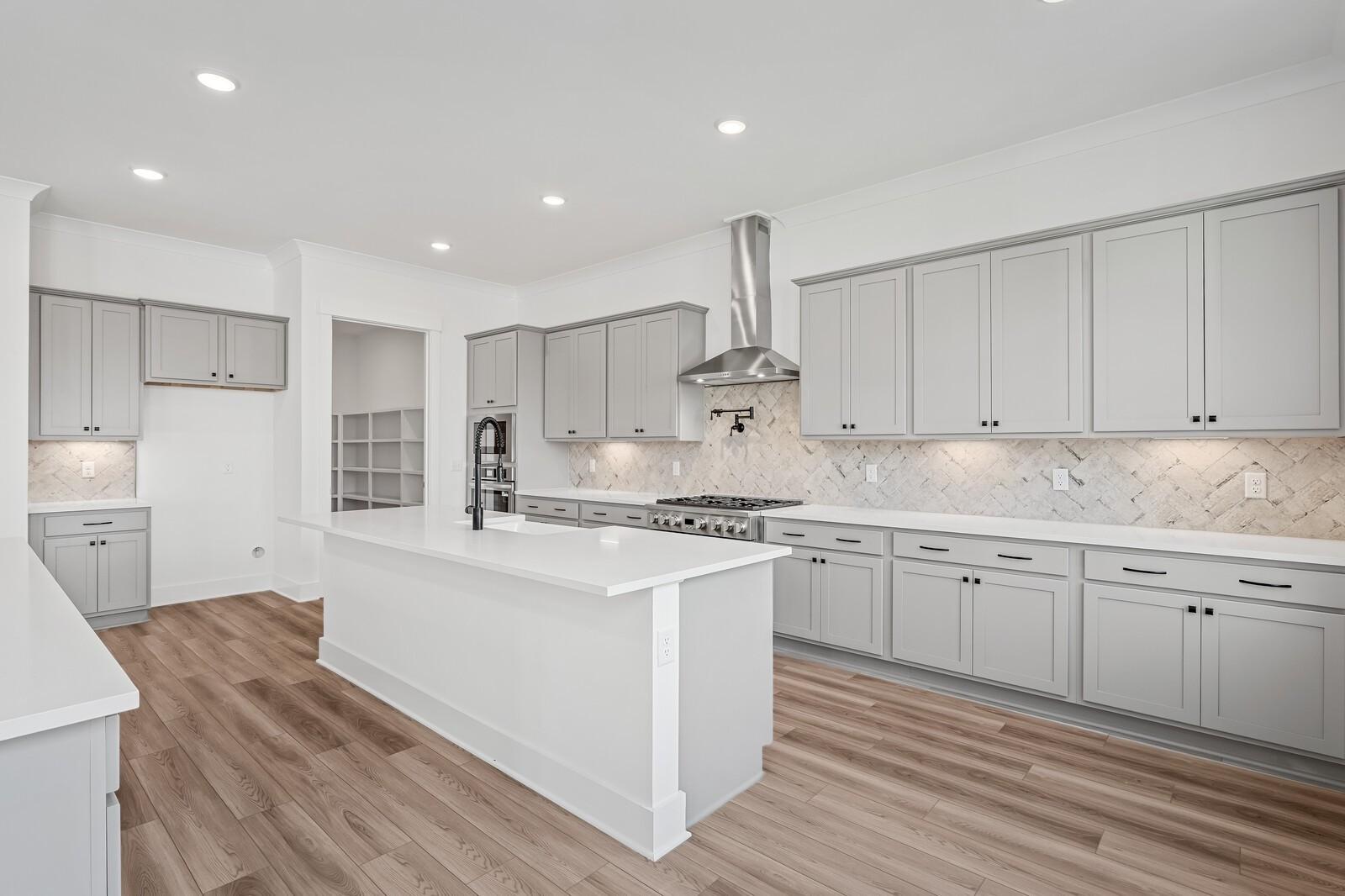 Modern kitchen featuring gray shaker cabinets, white quartz island, stainless gas range in The Alston A, Murfreesboro, TN