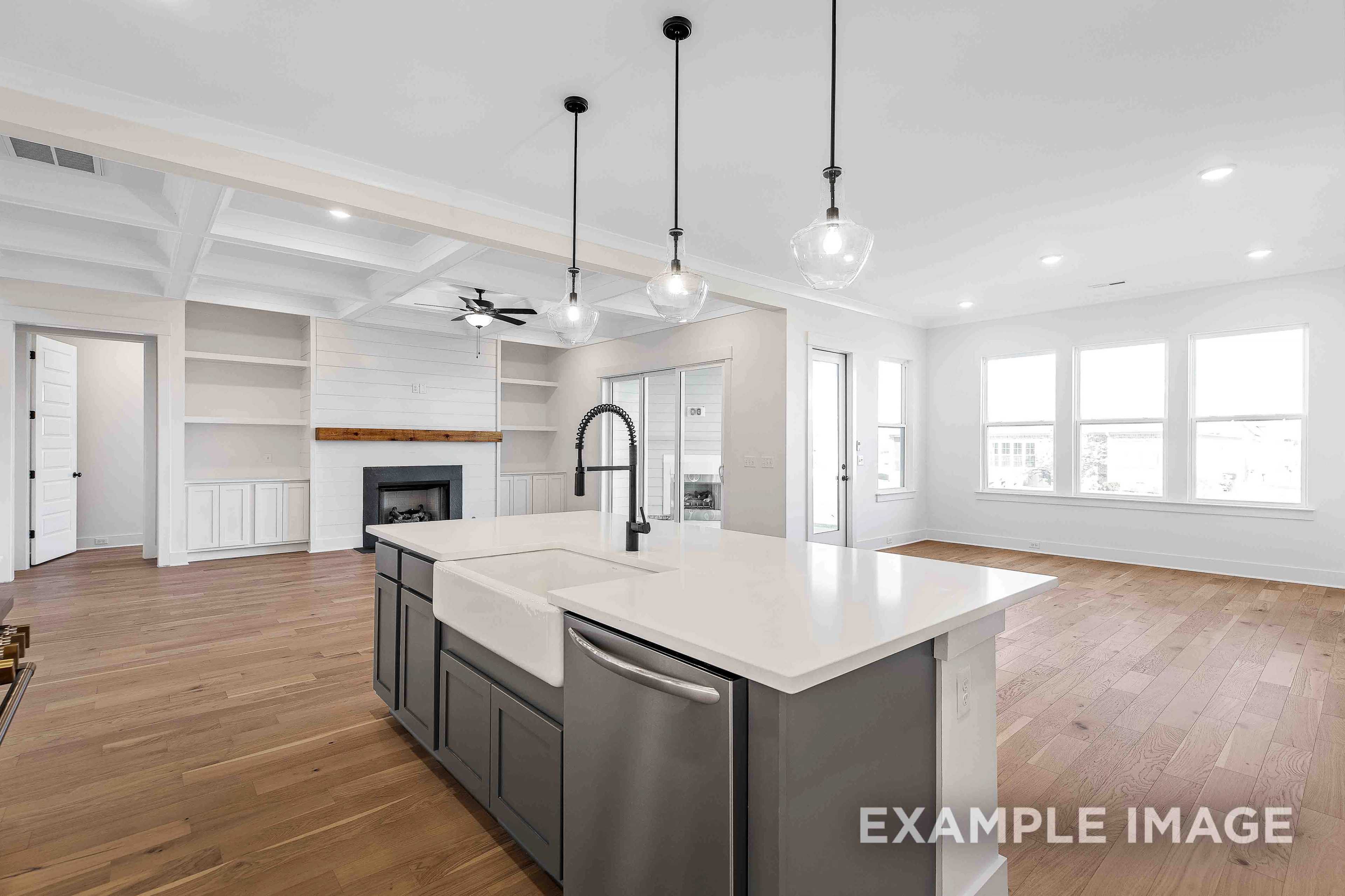 Spacious open-concept kitchen in The Albany A featuring quartz island, farmhouse sink, gray cabinets, and adjacent fireplace