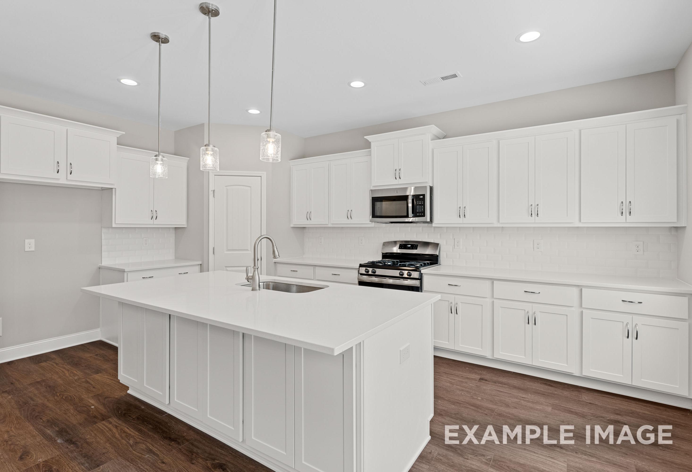 Spacious white kitchen in The Madison A by Davidson Homes featuring large center island, gas range, and pendant lights