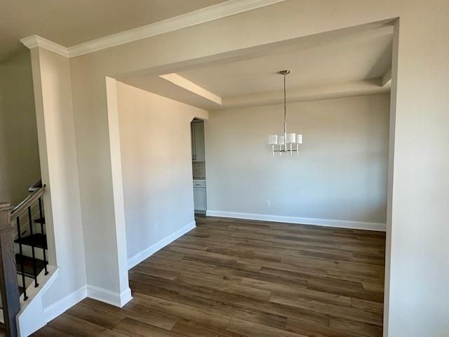 Elegant formal dining room with hardwood floors, modern chandelier, and arched kitchen entry in The Danbury C, Buford, GA