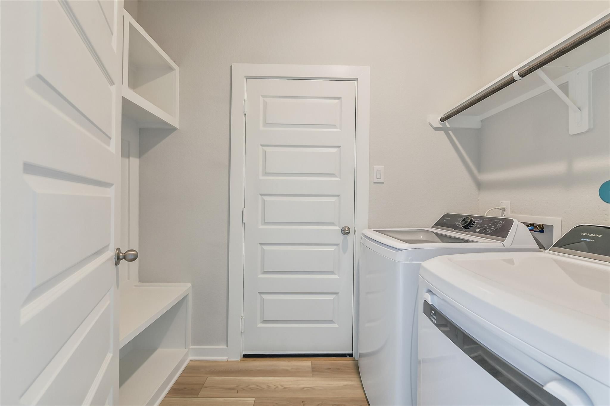 Functional laundry room with Frigidaire washer, dryer, built-in shelves, bench in Davidson Homes San Marcos E, Conroe, Texas