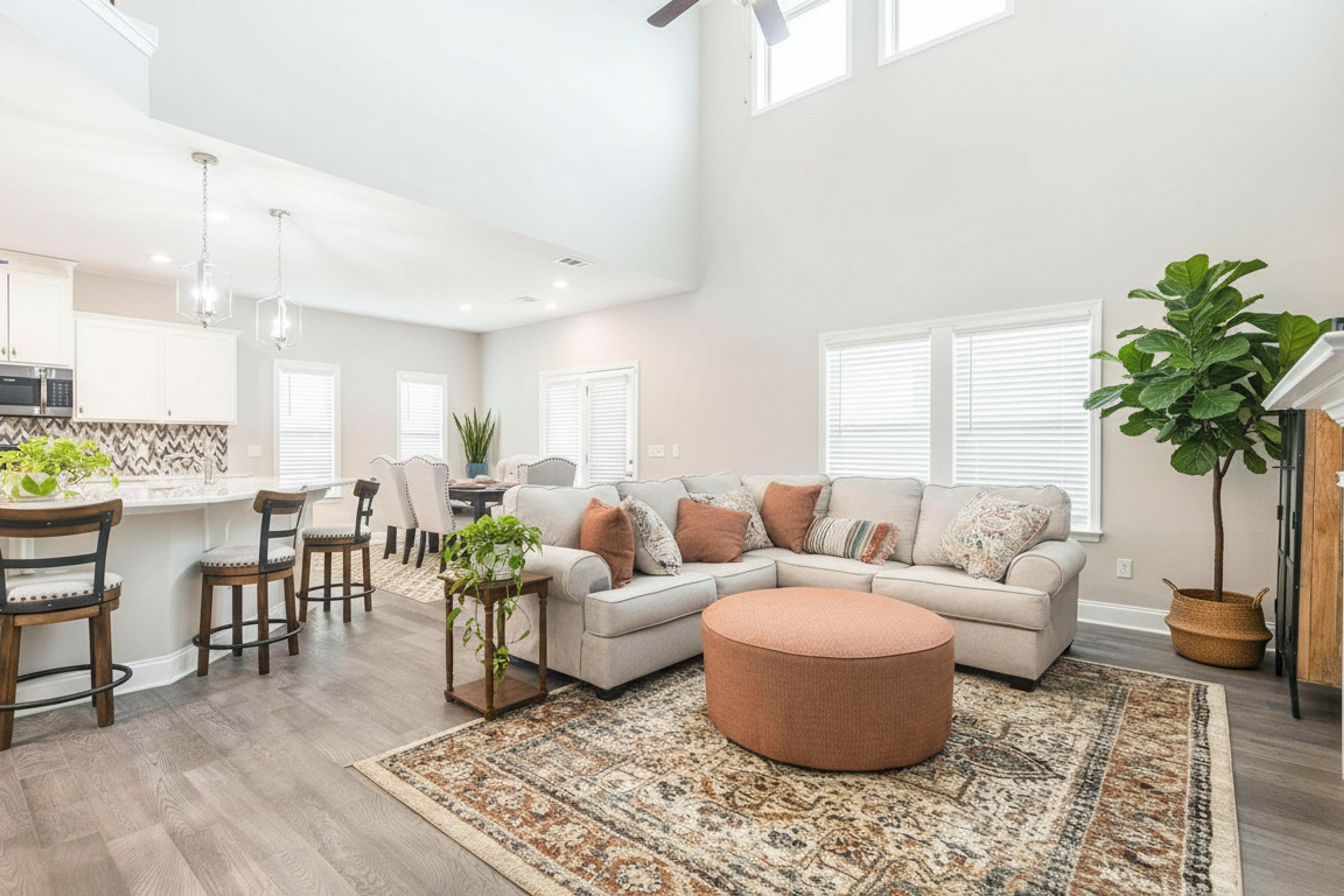 Spacious open-concept kitchen and living room at Links Crossing in Auburn AL with white island, beige sofa, Persian rug, and high ceilings