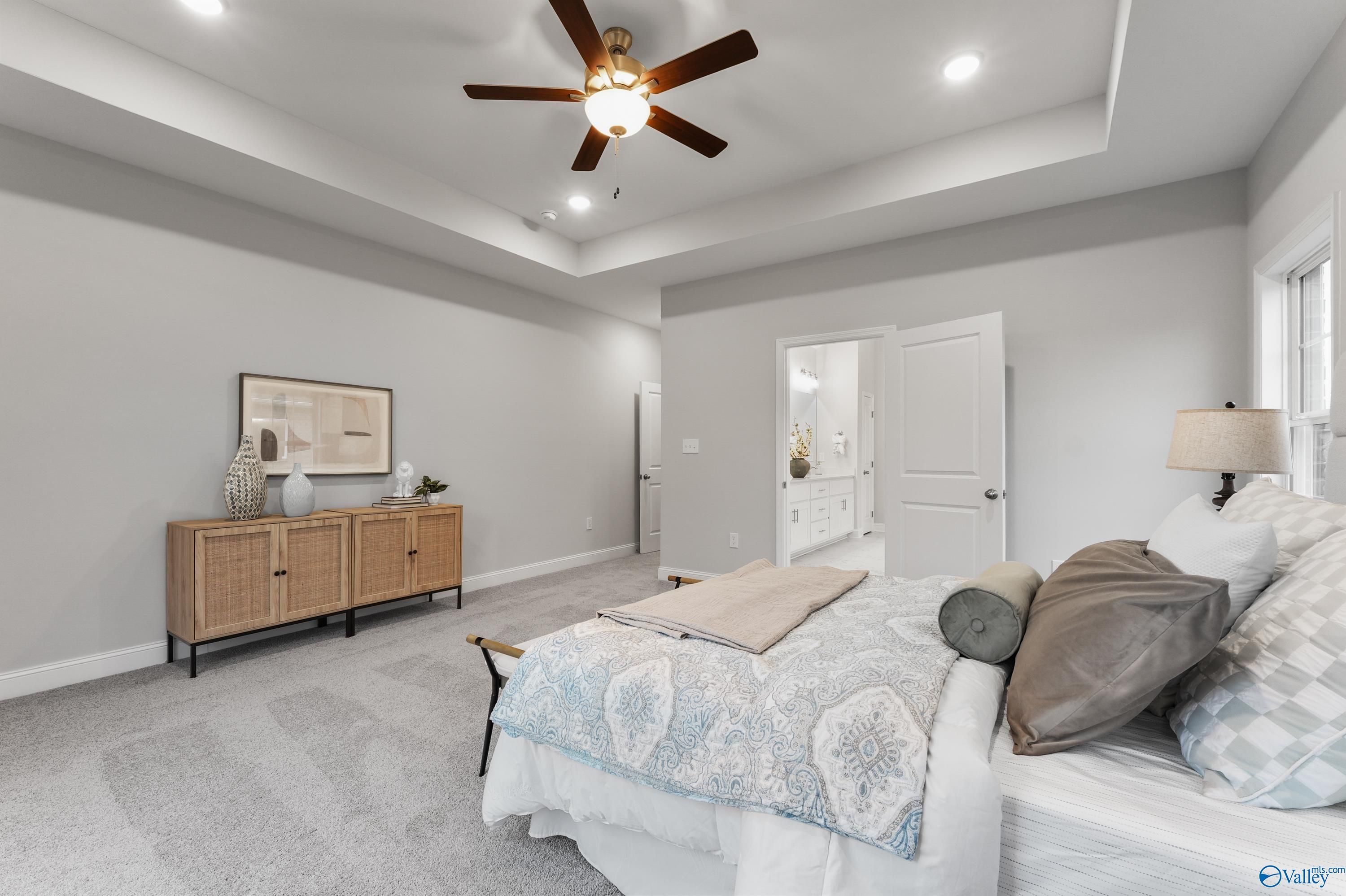Spacious master bedroom with ceiling fan, plush king bed, rattan dresser in Davidson Homes The Finleigh, Toney, Alabama