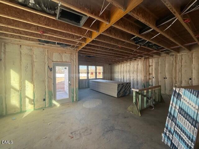 Under-construction garage framing with exposed beams, yellow insulation, wiring, and plywood in Davidson Homes Preston A, Lillington, NC