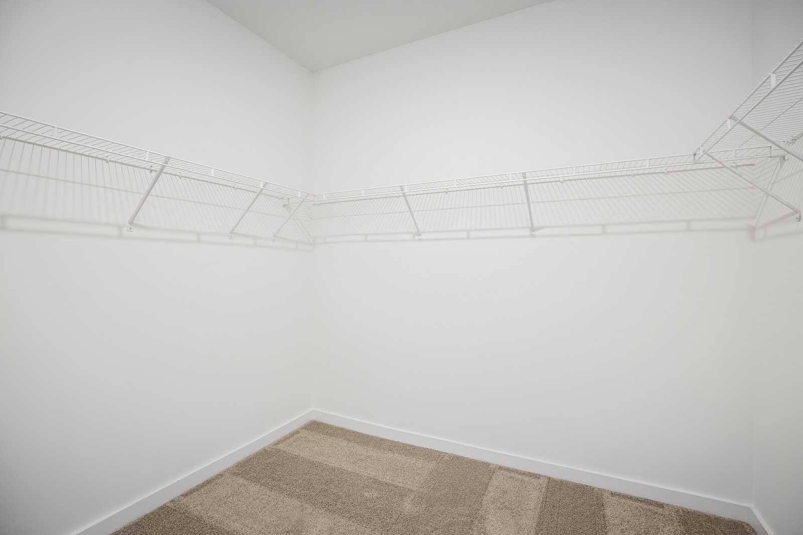 Spacious walk-in closet at Sage Farms in White House TN with white wire shelving and neutral carpet flooring