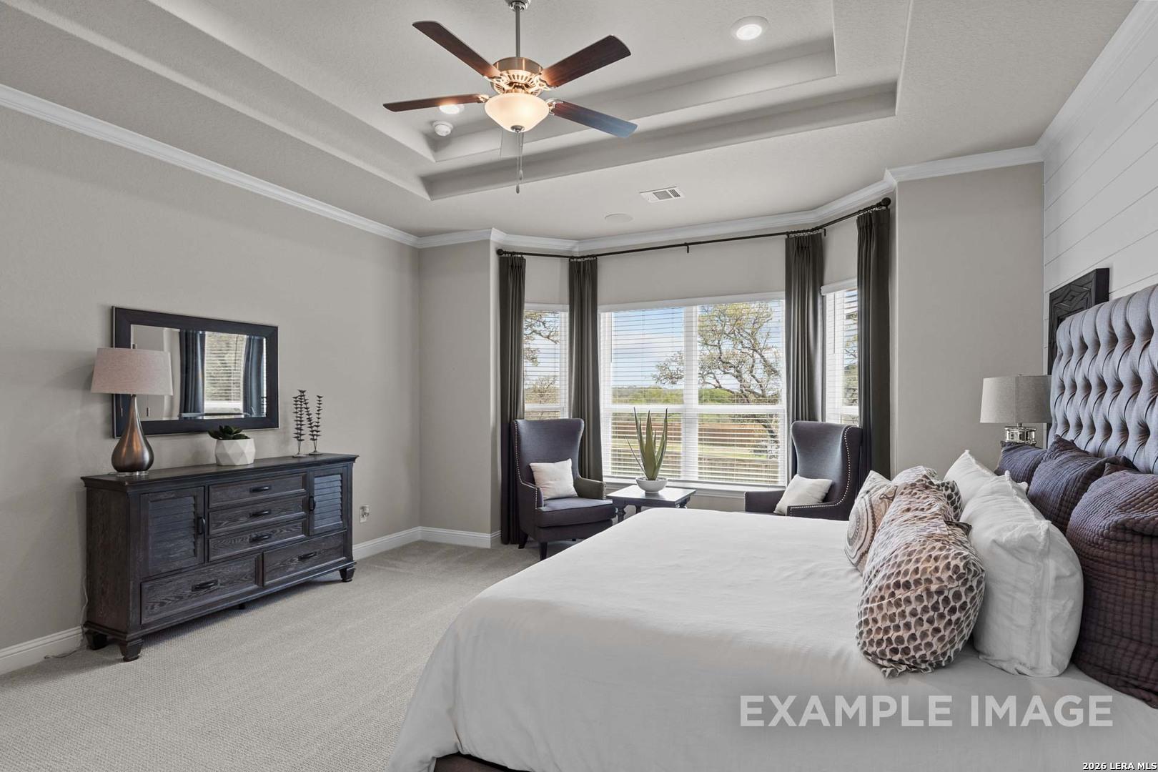 Spacious primary bedroom with tray ceiling and bay window seating in The Garner C plan at The Reserve at Potranco Oaks.