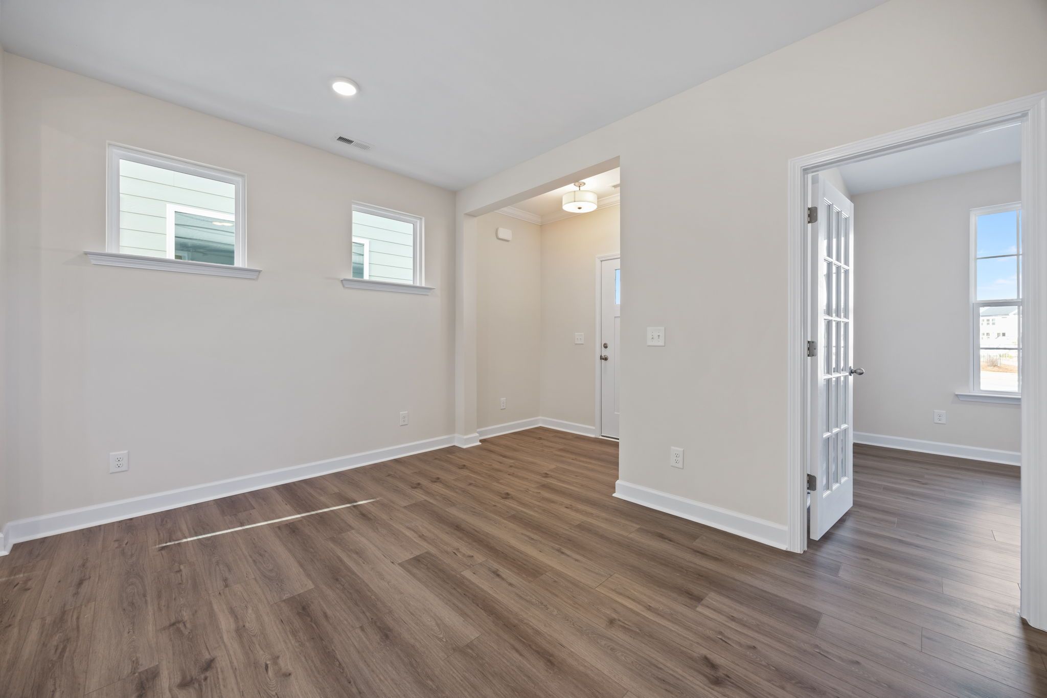 Bright home interior at Forestville Yard in Knightdale, NC by Davidson Homes with wood flooring and French door entryway.