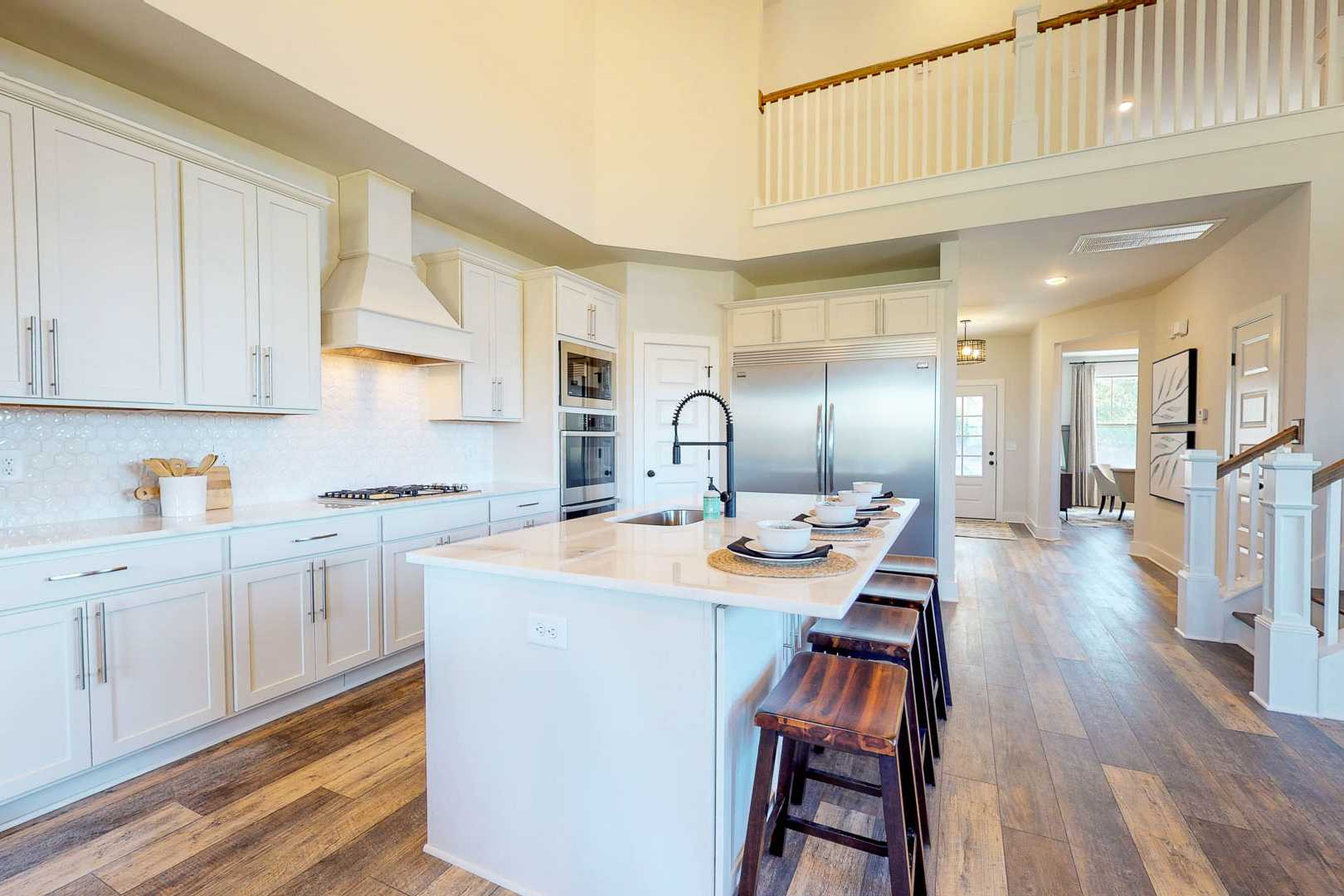 Spacious open-concept kitchen in Liberty Creek Gallatin TN with white shaker cabinets, large island, bar stools, and hardwood floors