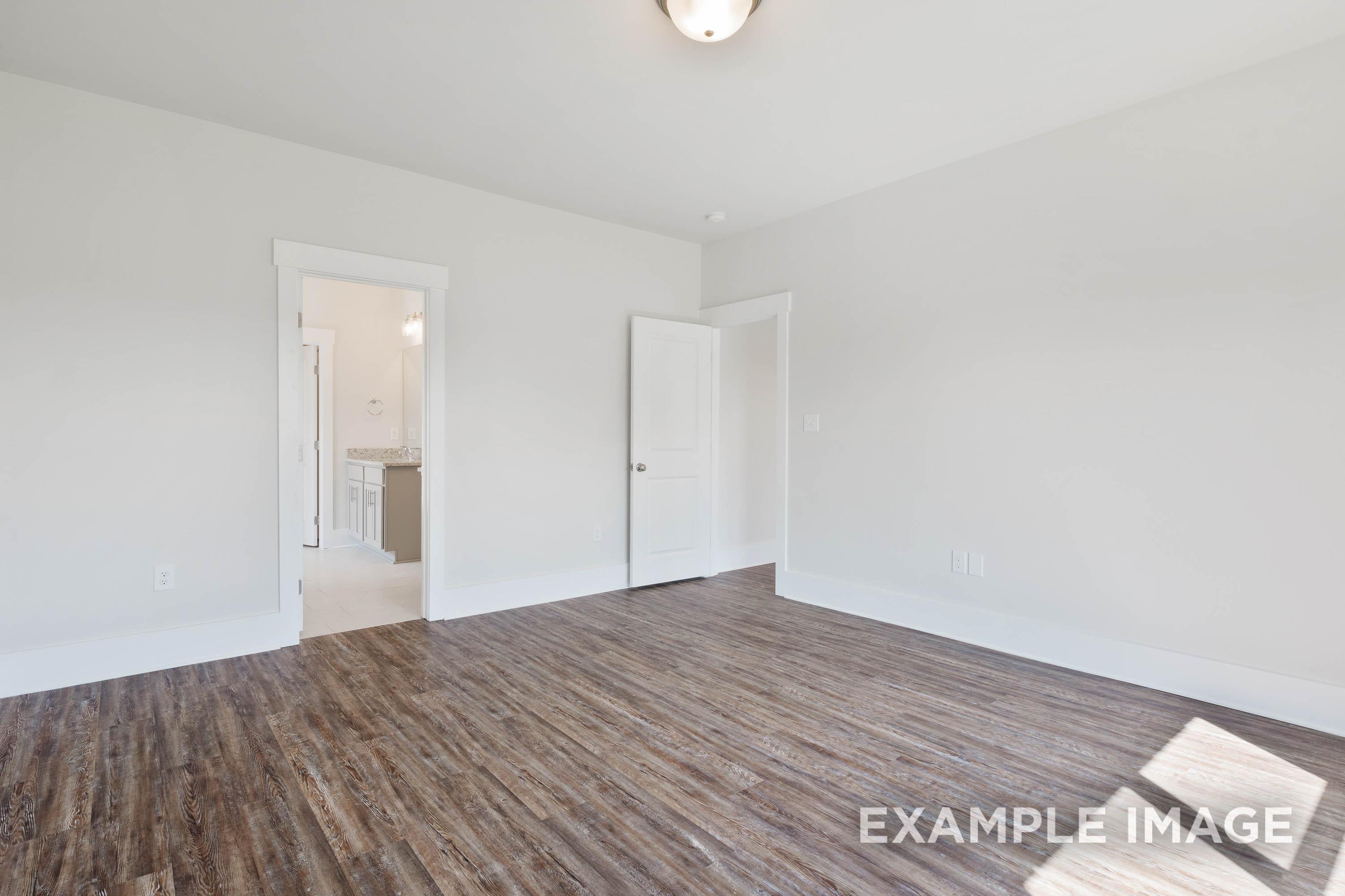 Spacious master suite with wood-look flooring and en suite bathroom in The Richmond D floor plan by Davidson Homes.