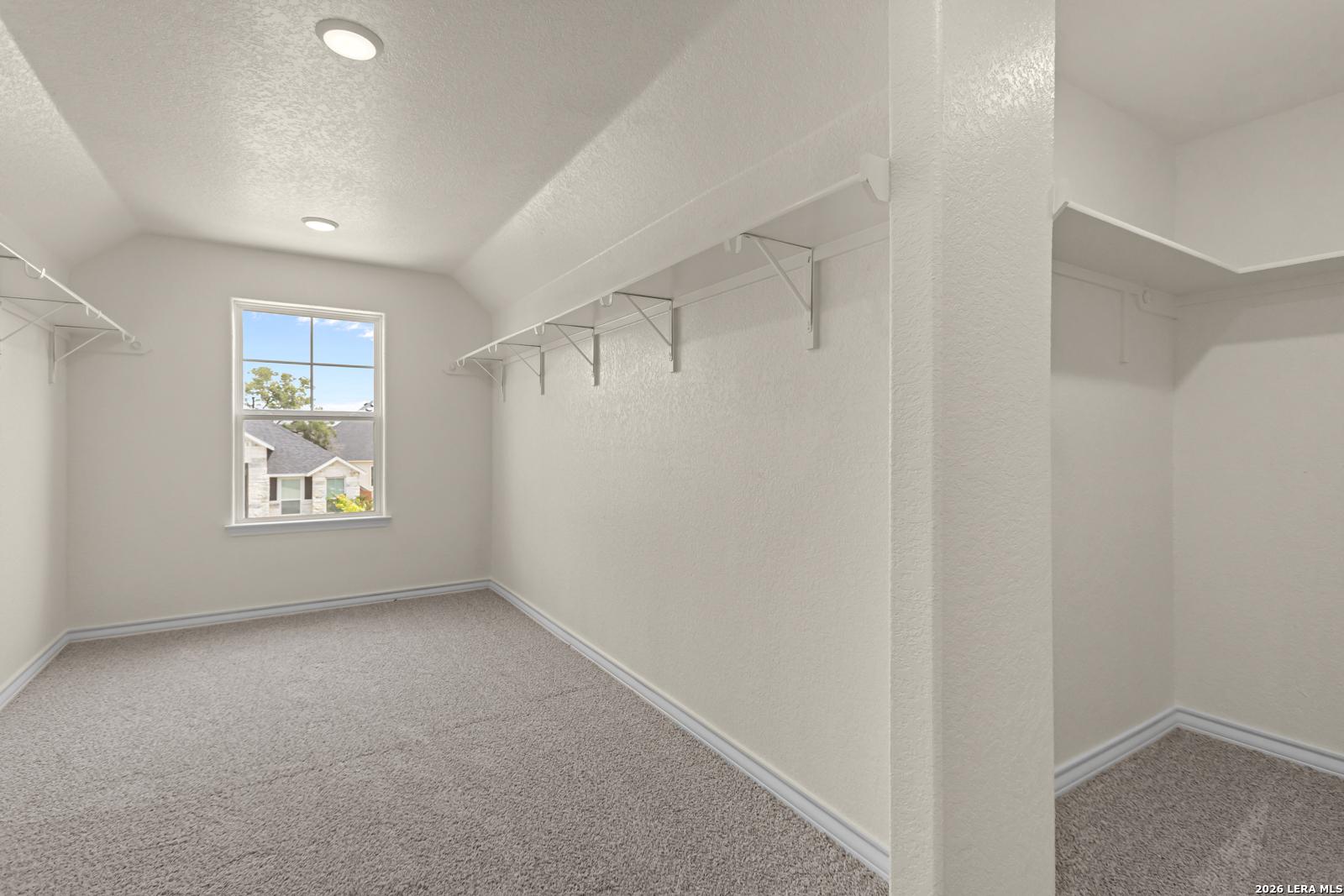 Spacious walk-in closet with shelving and natural light in The Danbury H model home, The Reserve at Potranco Oaks.