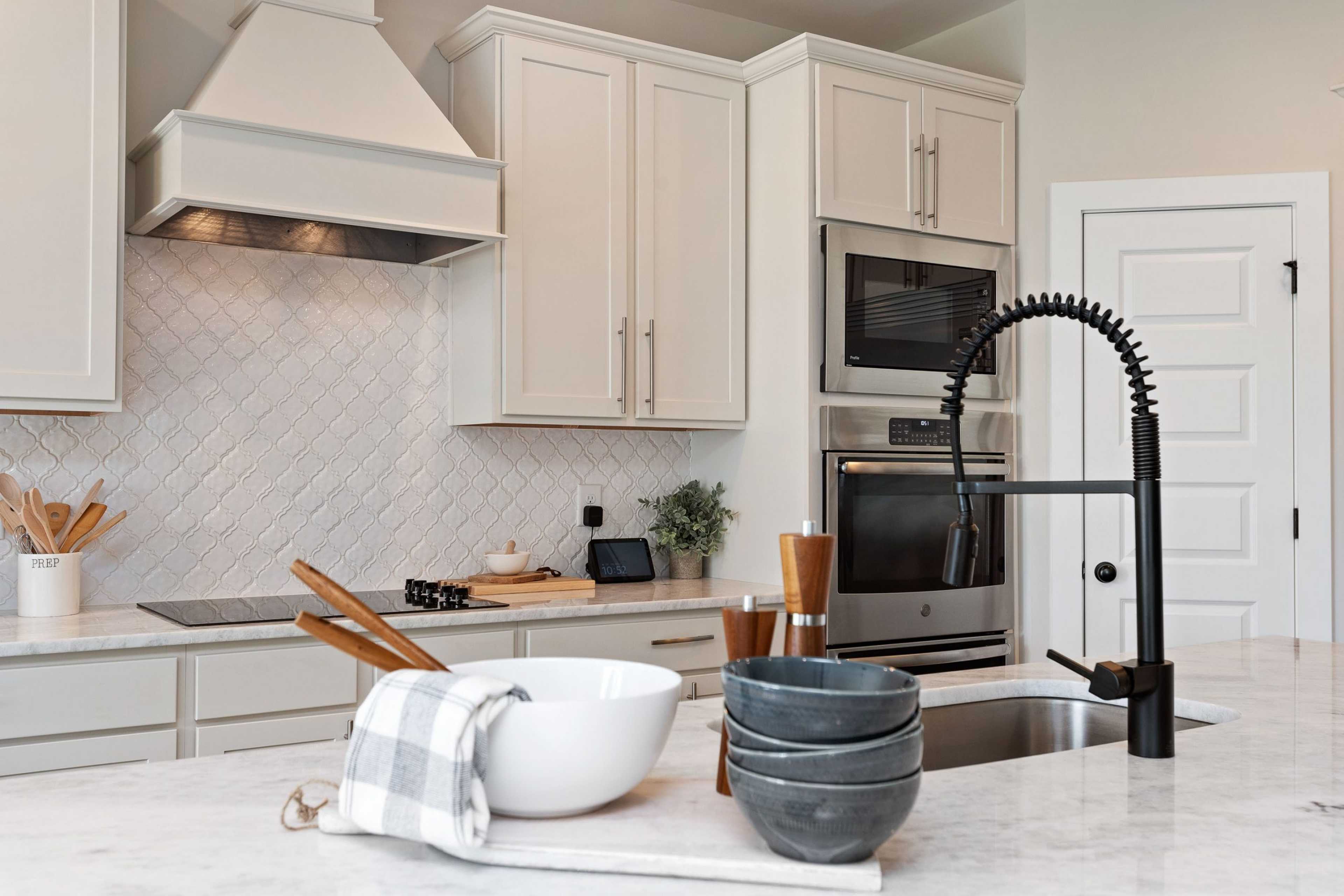 Spacious Rivers Edge kitchen in Murfreesboro TN with white shaker cabinets, herringbone subway tile backsplash, black pull-down faucet, and stainless appliances