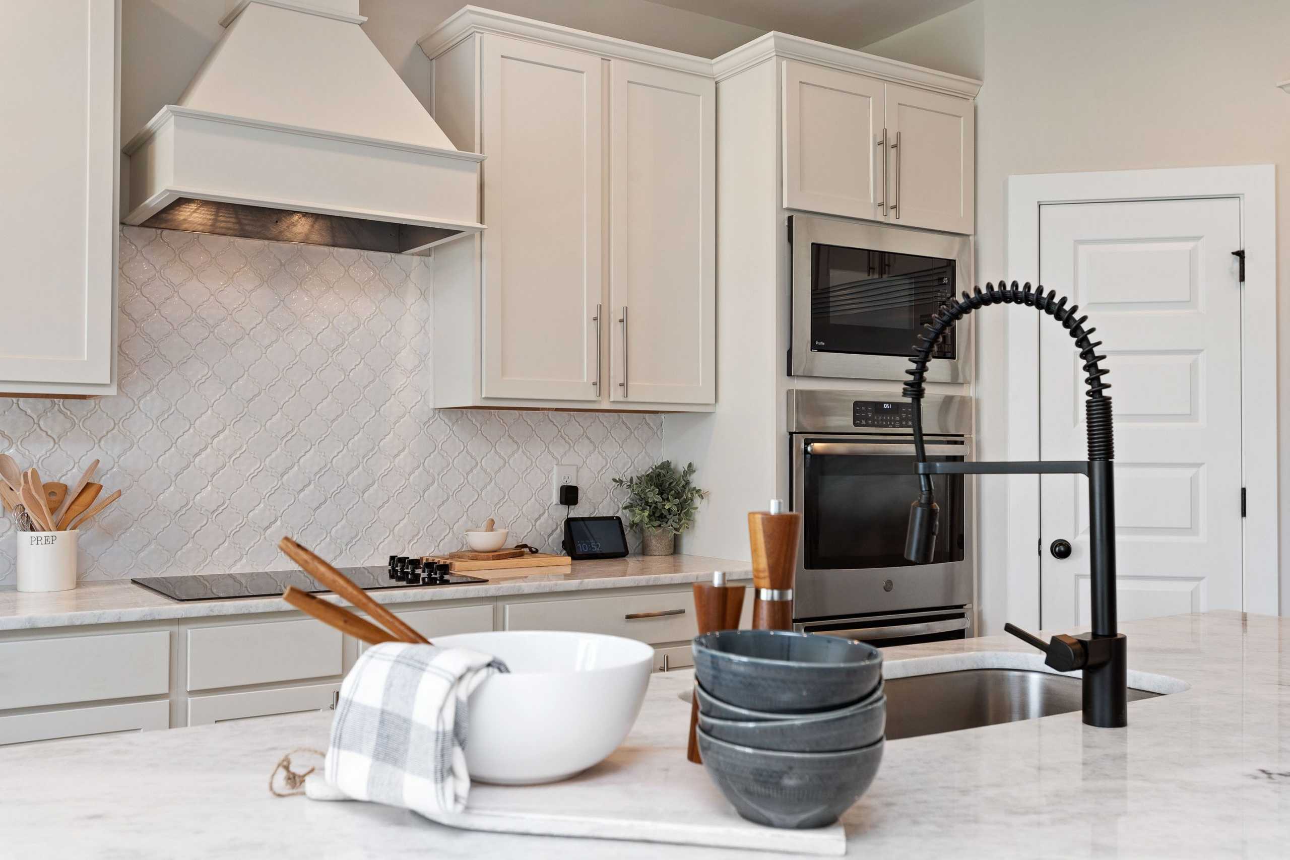 Spacious Rivers Edge kitchen in Murfreesboro TN with white shaker cabinets, herringbone subway tile backsplash, black pull-down faucet, and stainless appliances
