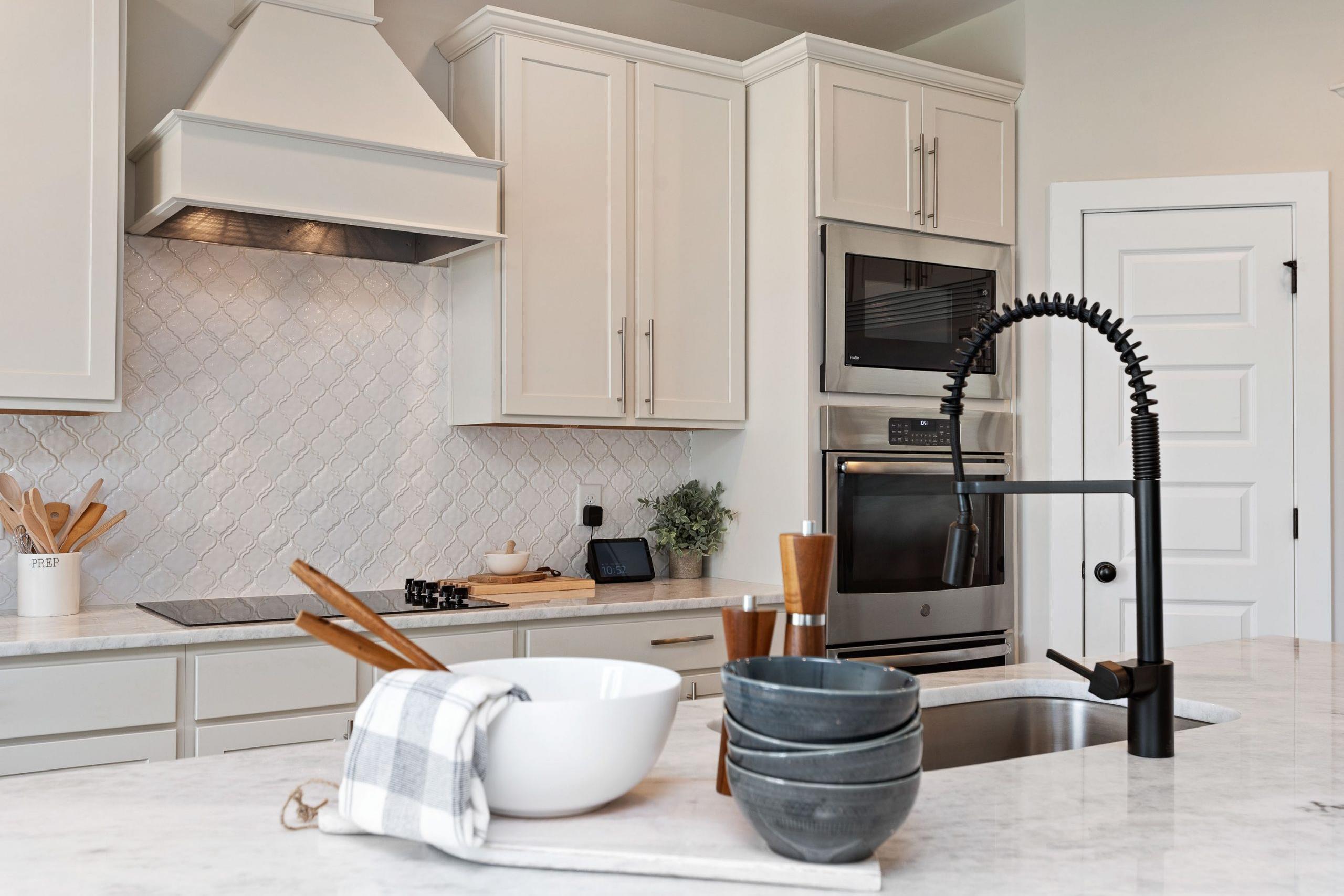 Spacious Rivers Edge kitchen in Murfreesboro TN with white shaker cabinets, herringbone subway tile backsplash, black pull-down faucet, and stainless appliances