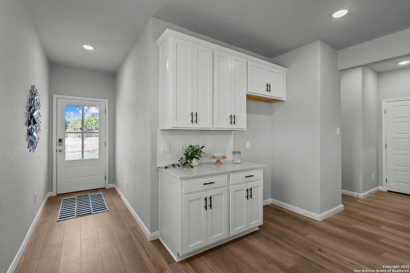 Bright mudroom with white shaker cabinets, gray walls, and hardwood floors in Davidson Homes The Gillian C, San Antonio