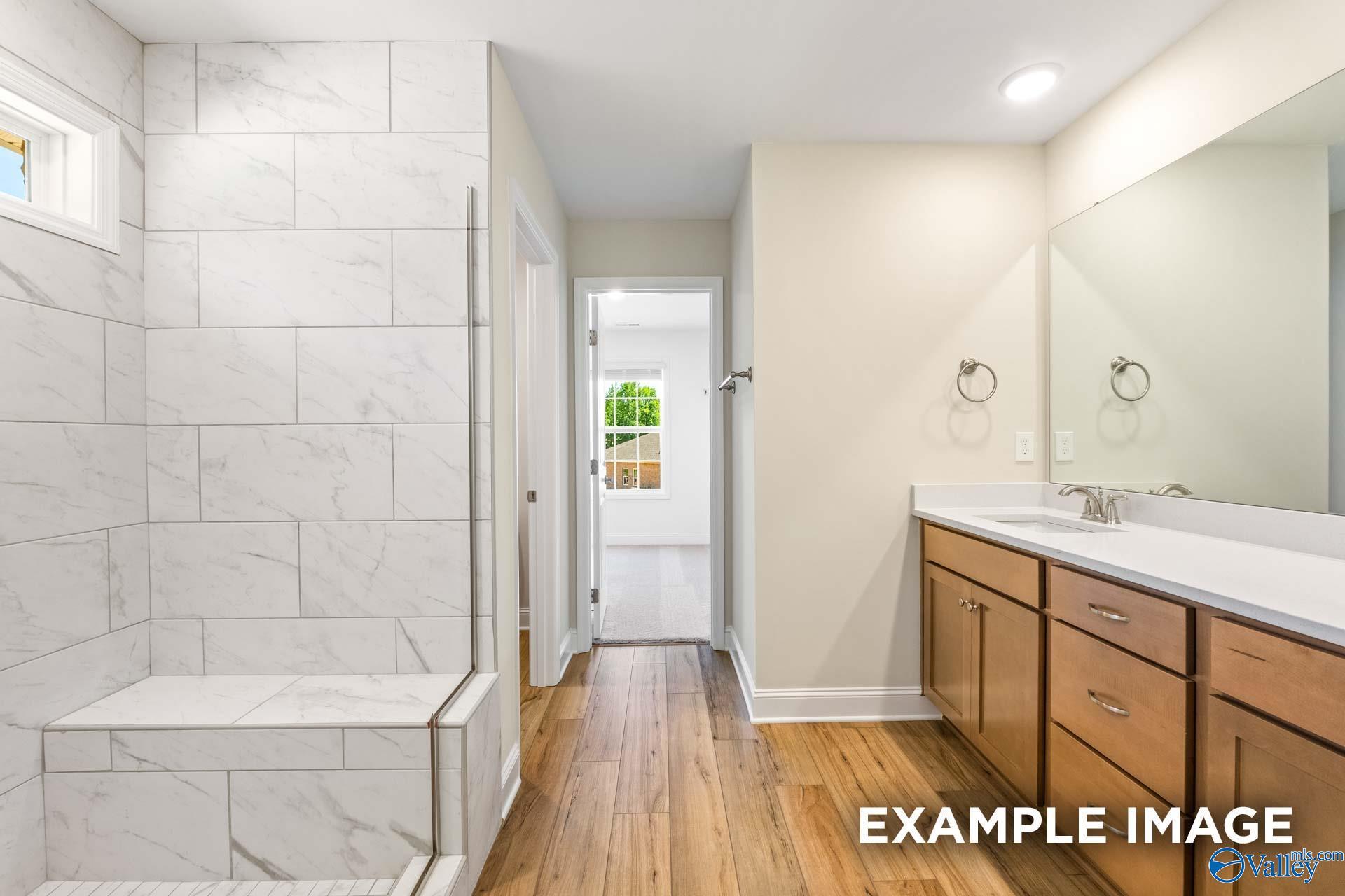 Elegant master bathroom featuring marble tiled shower, double vanity, and hardwood floors in Davidson Homes The Shelby B, Owens Cross Roads