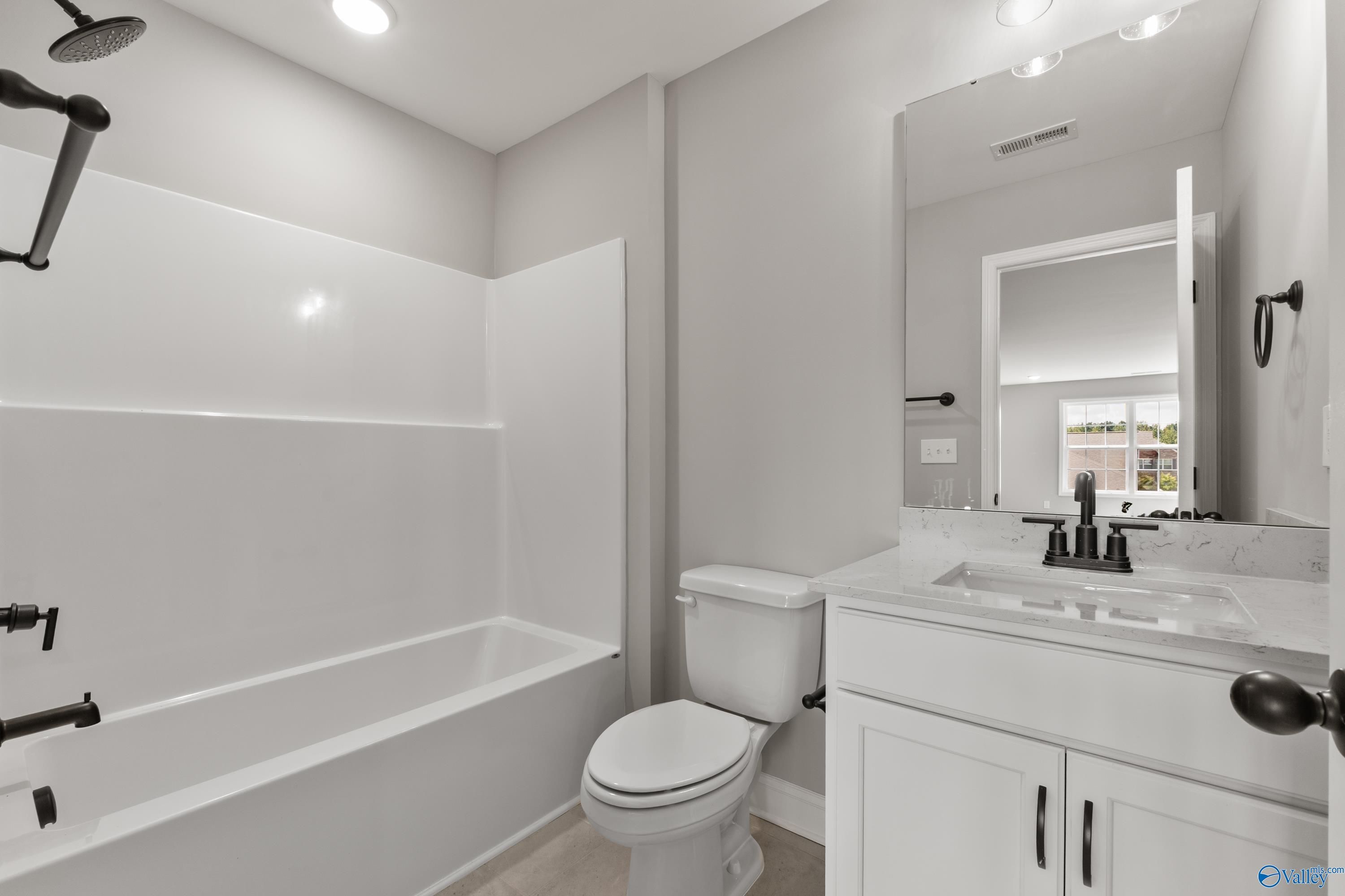 Elegant secondary bathroom with white tub-shower combo, modern black fixtures, and vanity in Davidson Homes The Montgomery B With Bonus, Toney, Alabama