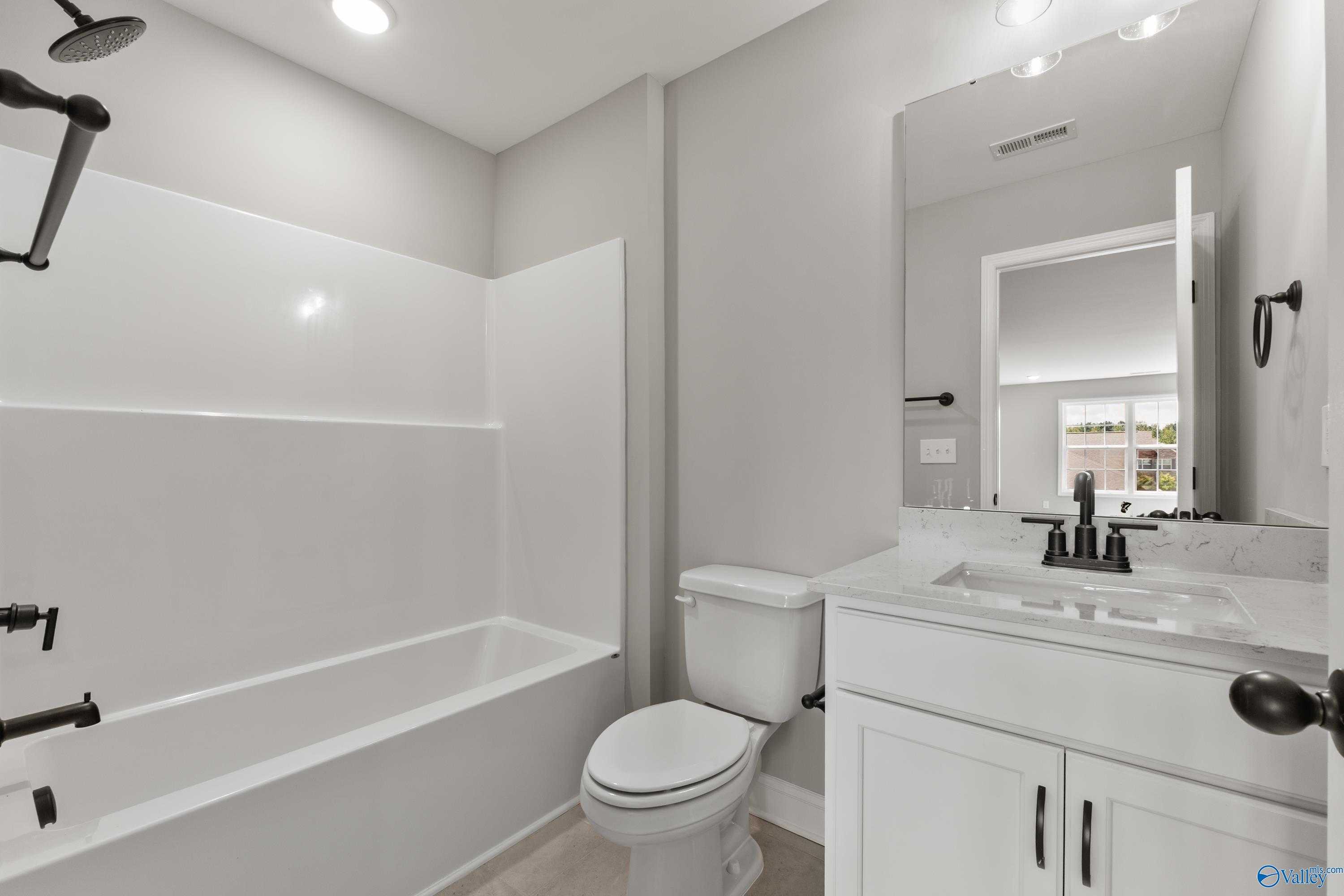 Elegant secondary bathroom with white tub-shower combo, modern black fixtures, and vanity in Davidson Homes The Montgomery B With Bonus, Toney, Alabama