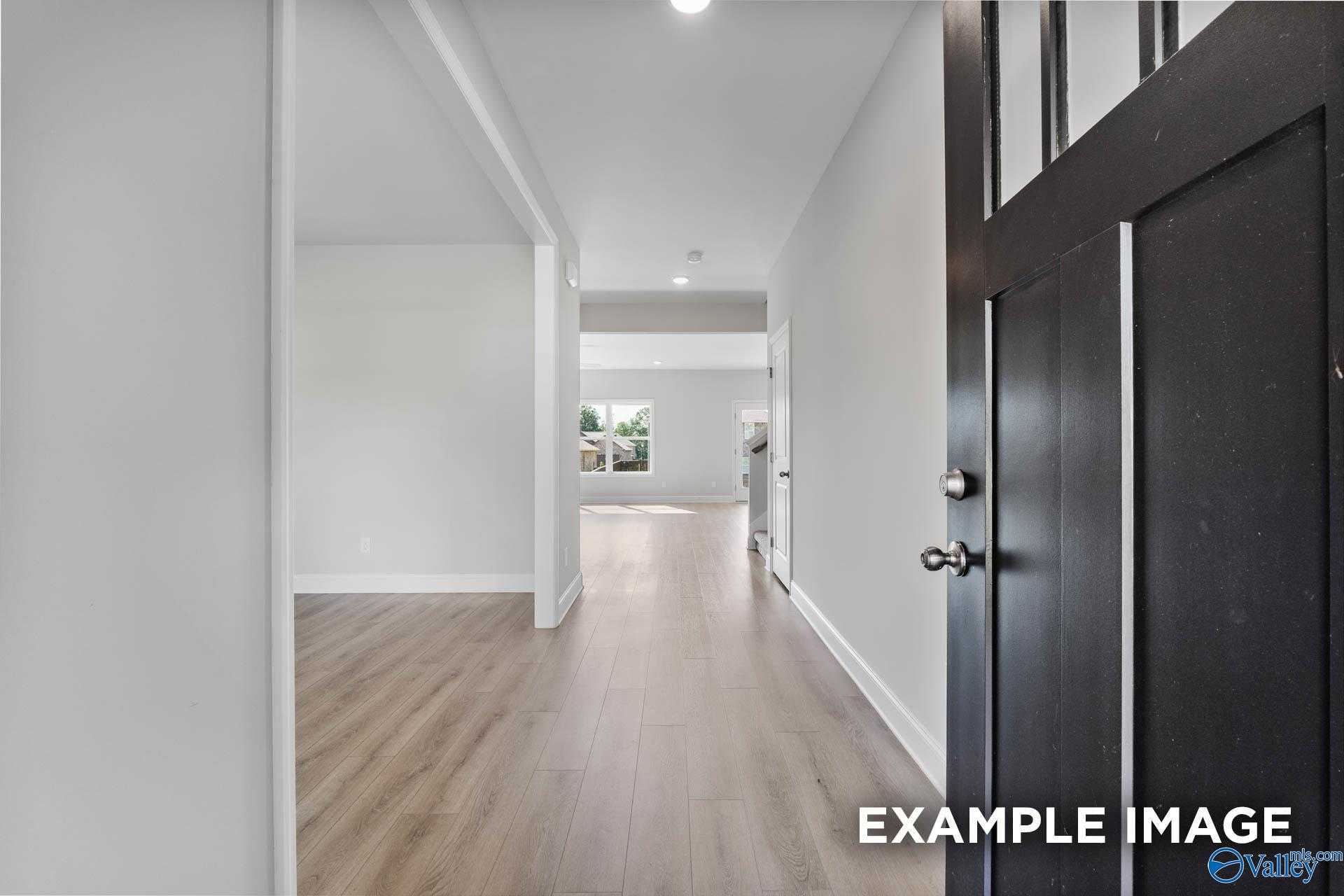 Bright hallway with light wood floors, white walls, and arched openings in Davidson Homes The Chelsea C, Athens, Alabama