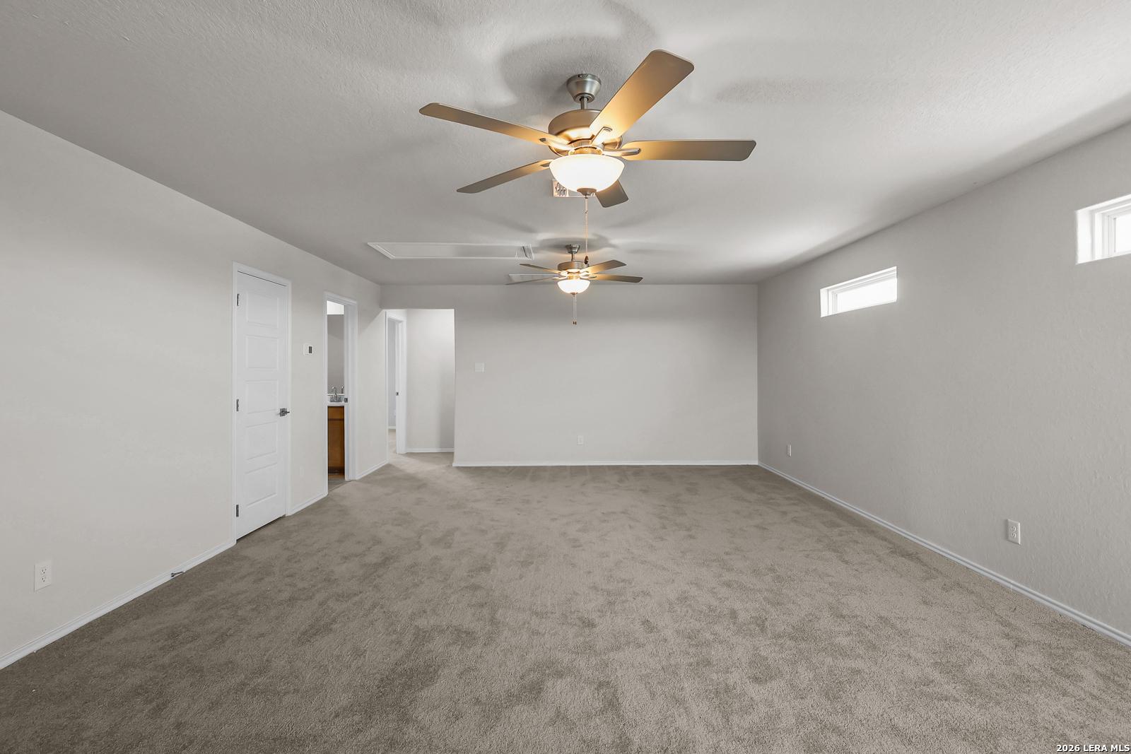 Spacious carpeted game room with dual ceiling fans in The San Marcos F floor plan at Rayburn Valley, San Antonio.