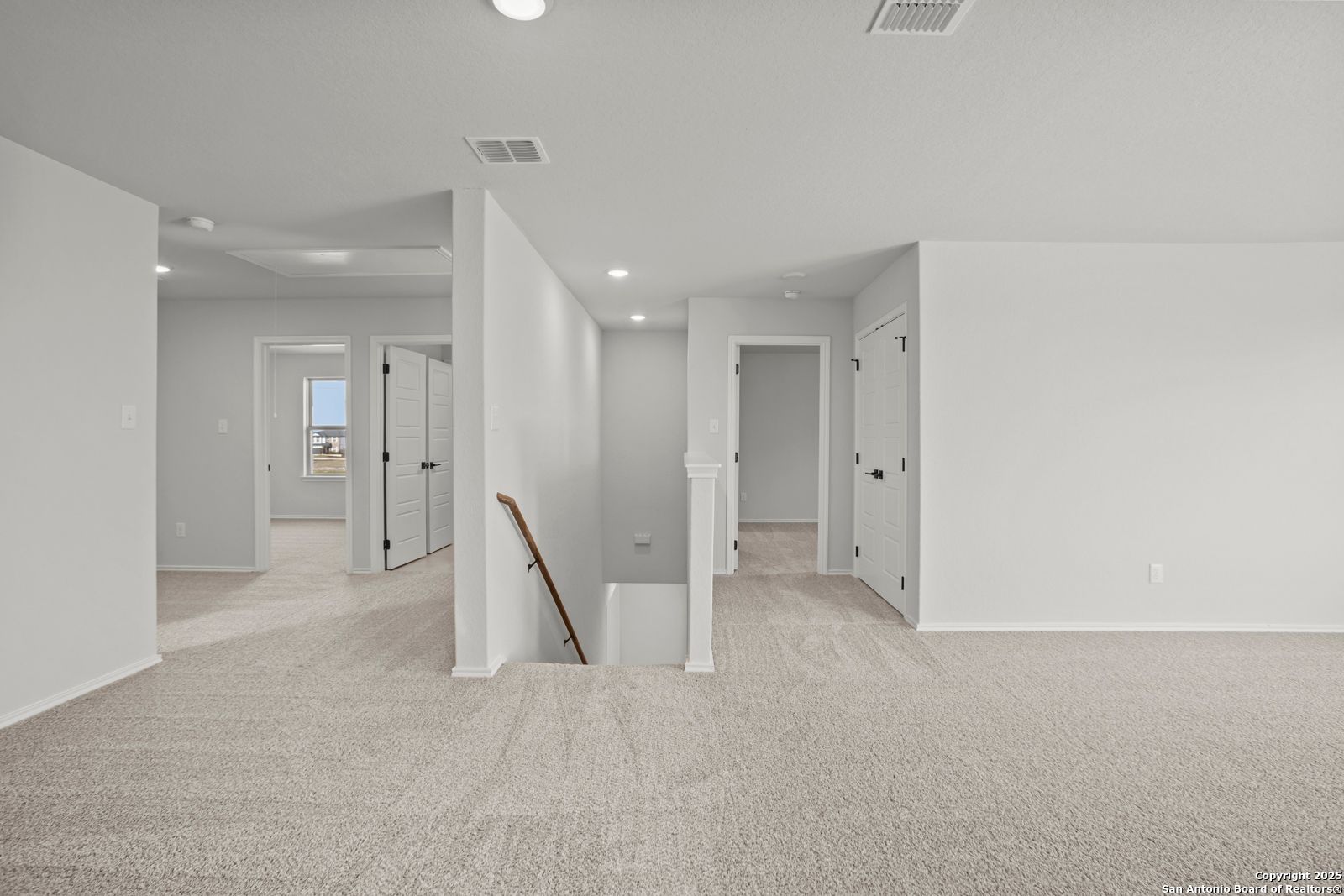 Spacious upstairs hallway with multiple bedroom doors and carpeted staircase in Davidson Homes The Douglas C, Seguin, Texas