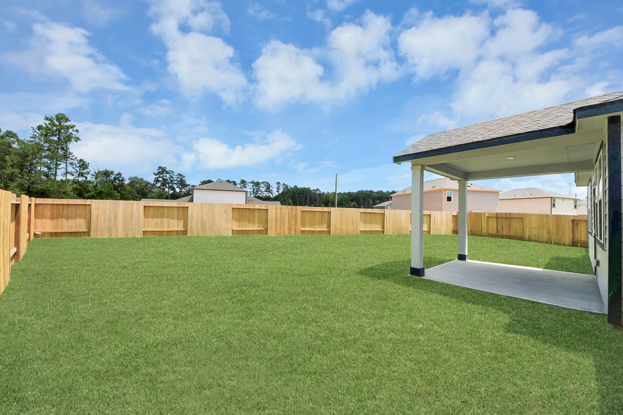 Covered back patio and spacious fenced backyard at The Sabine F home in Liberty Estates, Cleveland, Texas.