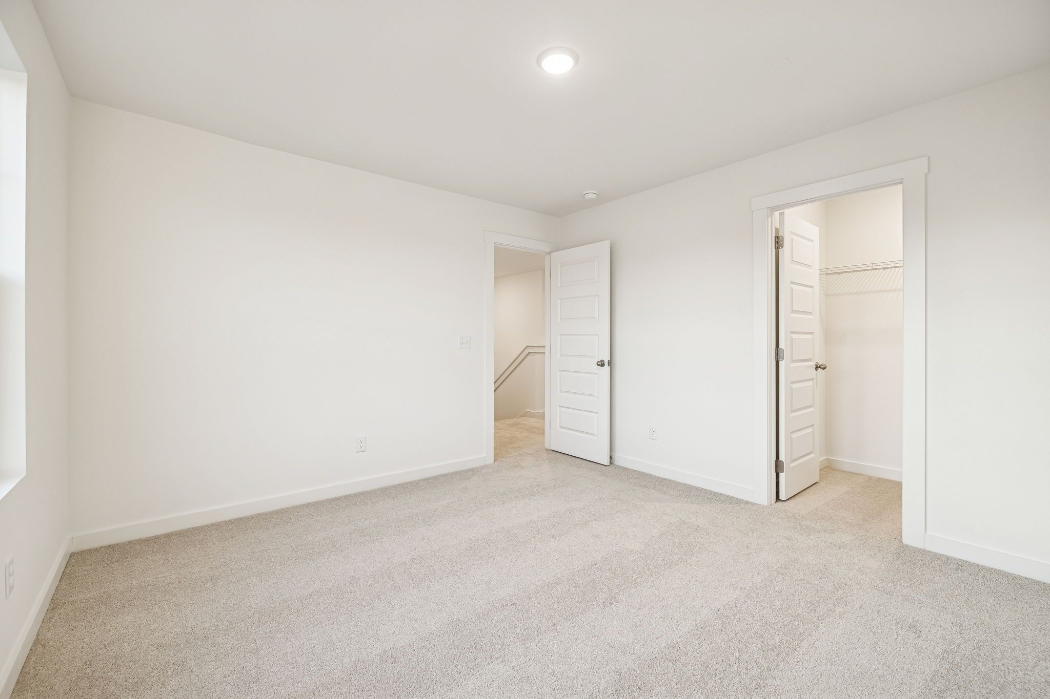 Spacious upstairs bedroom with walk-in closet, en-suite bath access, and neutral carpet in The Willow by Davidson Homes, White House TN