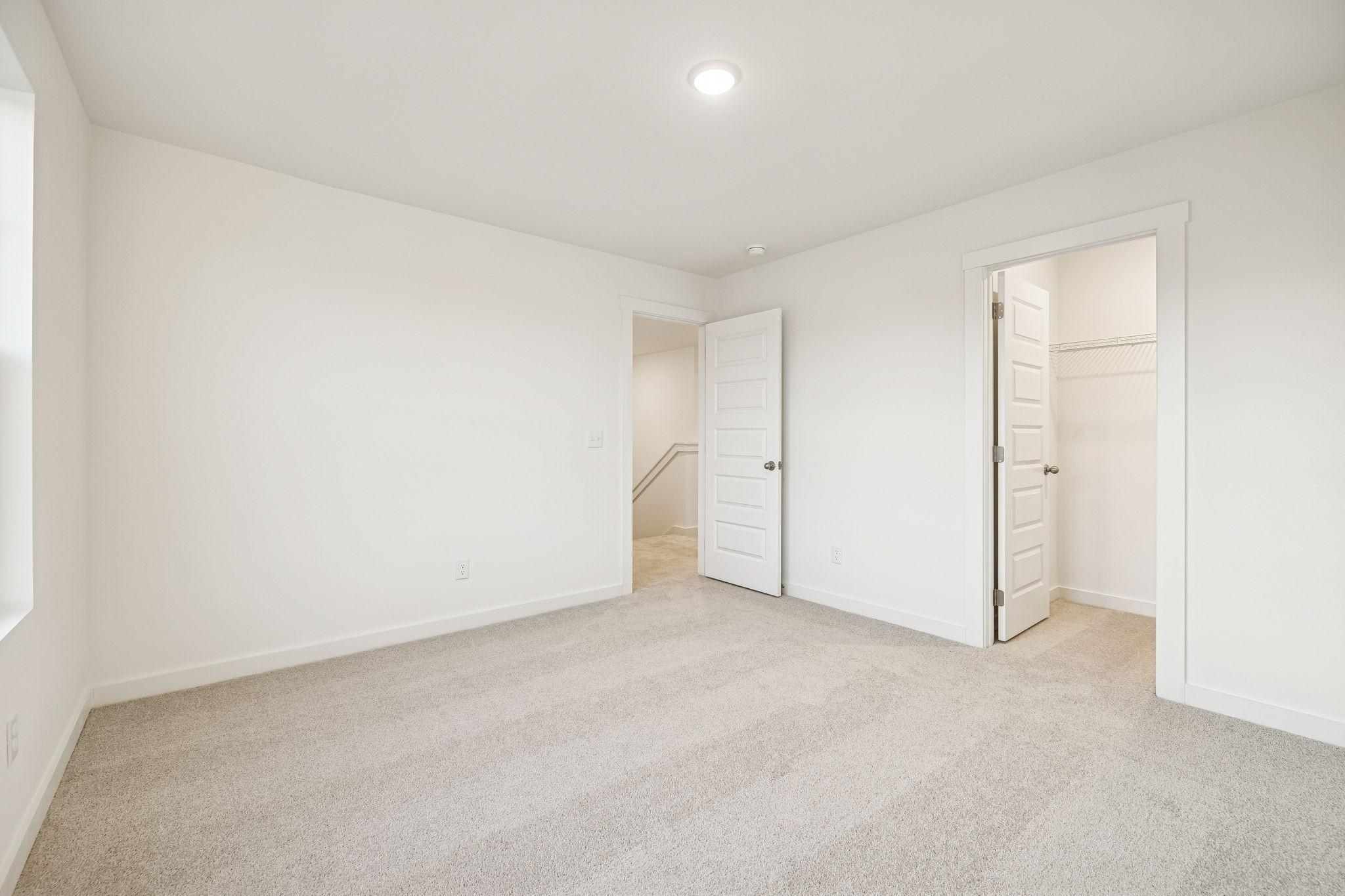 Spacious upstairs bedroom with walk-in closet, en-suite bath access, and neutral carpet in The Willow by Davidson Homes, White House TN