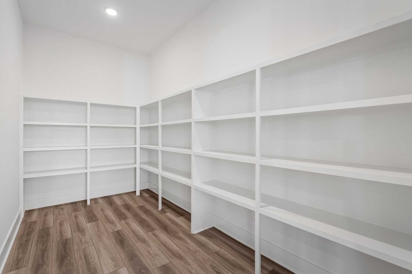 Spacious walk-in closet with custom white built-in shelving and hardwood floors in Davidson Homes The Alston A, Murfreesboro, TN