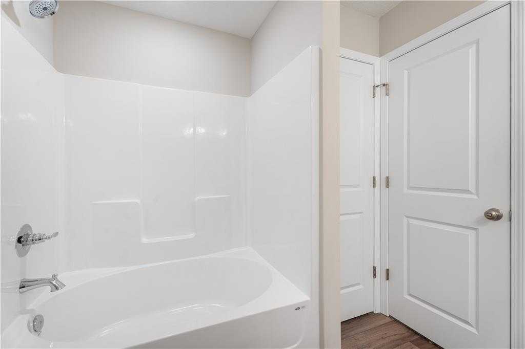 White bathtub and tiled shower combo in modern master bathroom, Evermore Homes The Washington, Phenix City, Alabama