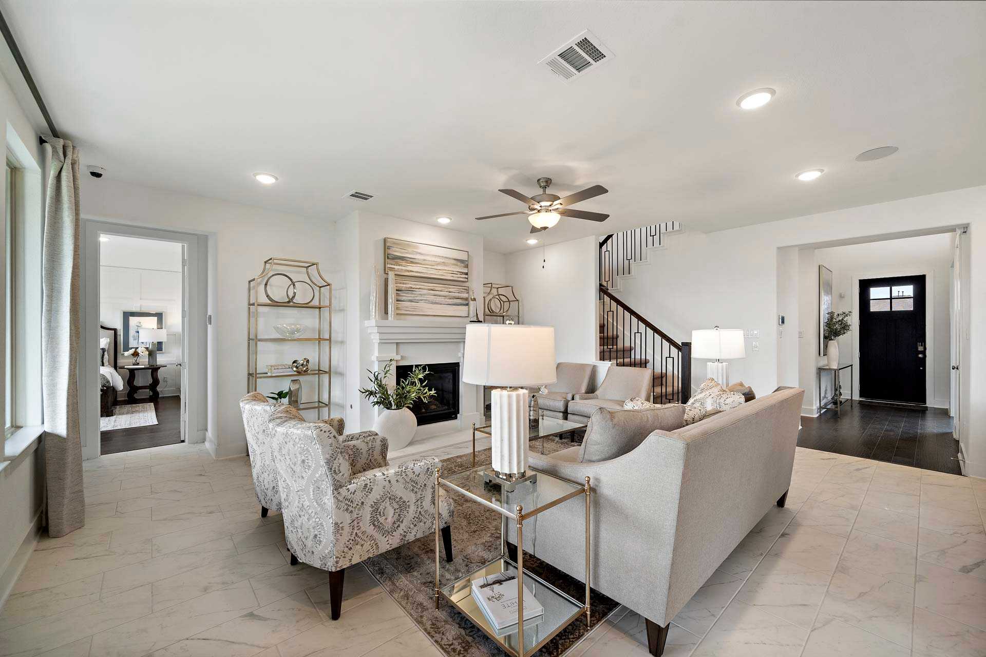 Spacious open-concept living room in Sierra Vista Rosharon Texas featuring neutral furniture, gas fireplace, staircase and ceiling fan