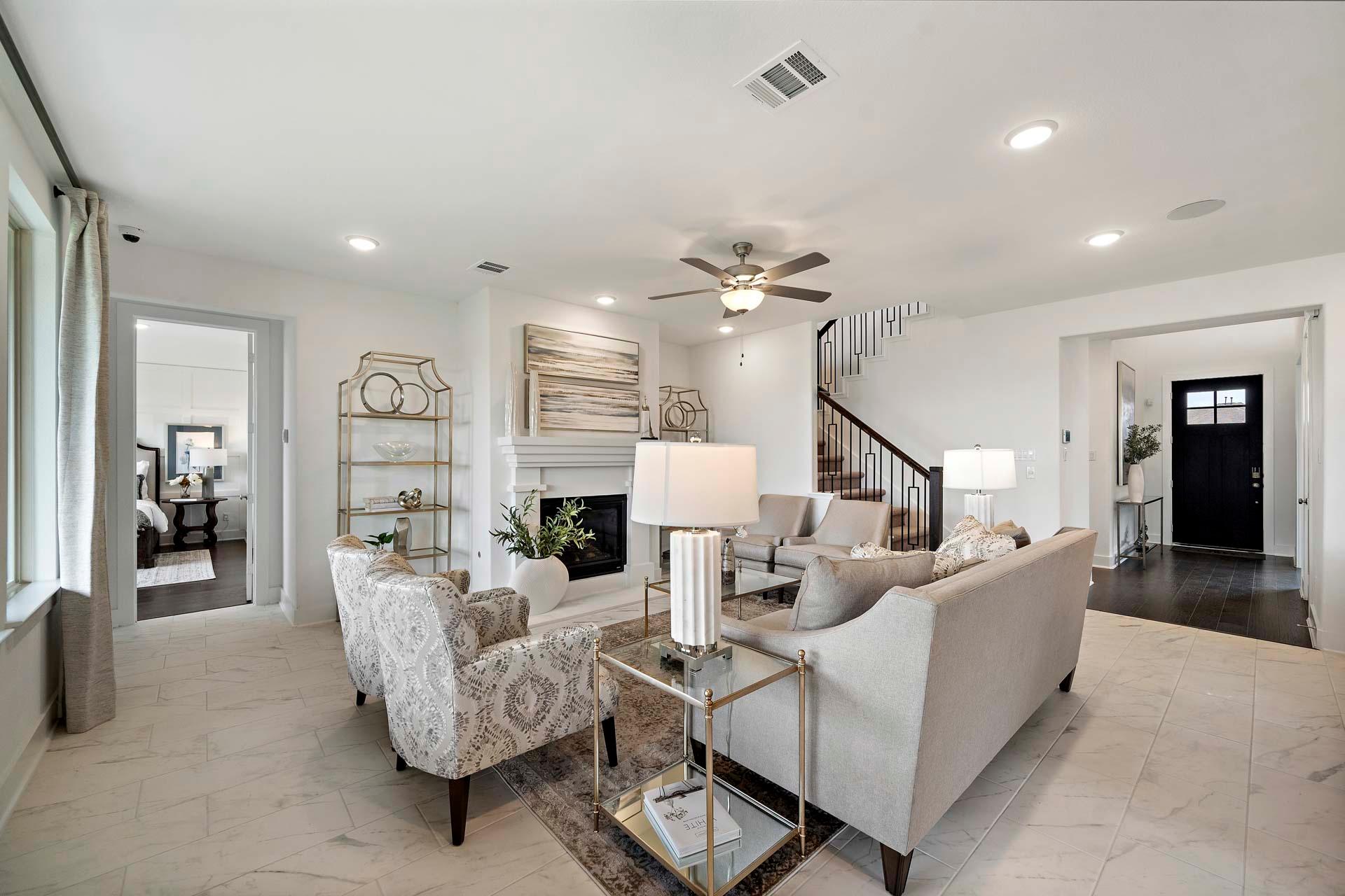 Spacious open-concept living room in Sierra Vista Rosharon Texas featuring neutral furniture, gas fireplace, staircase and ceiling fan