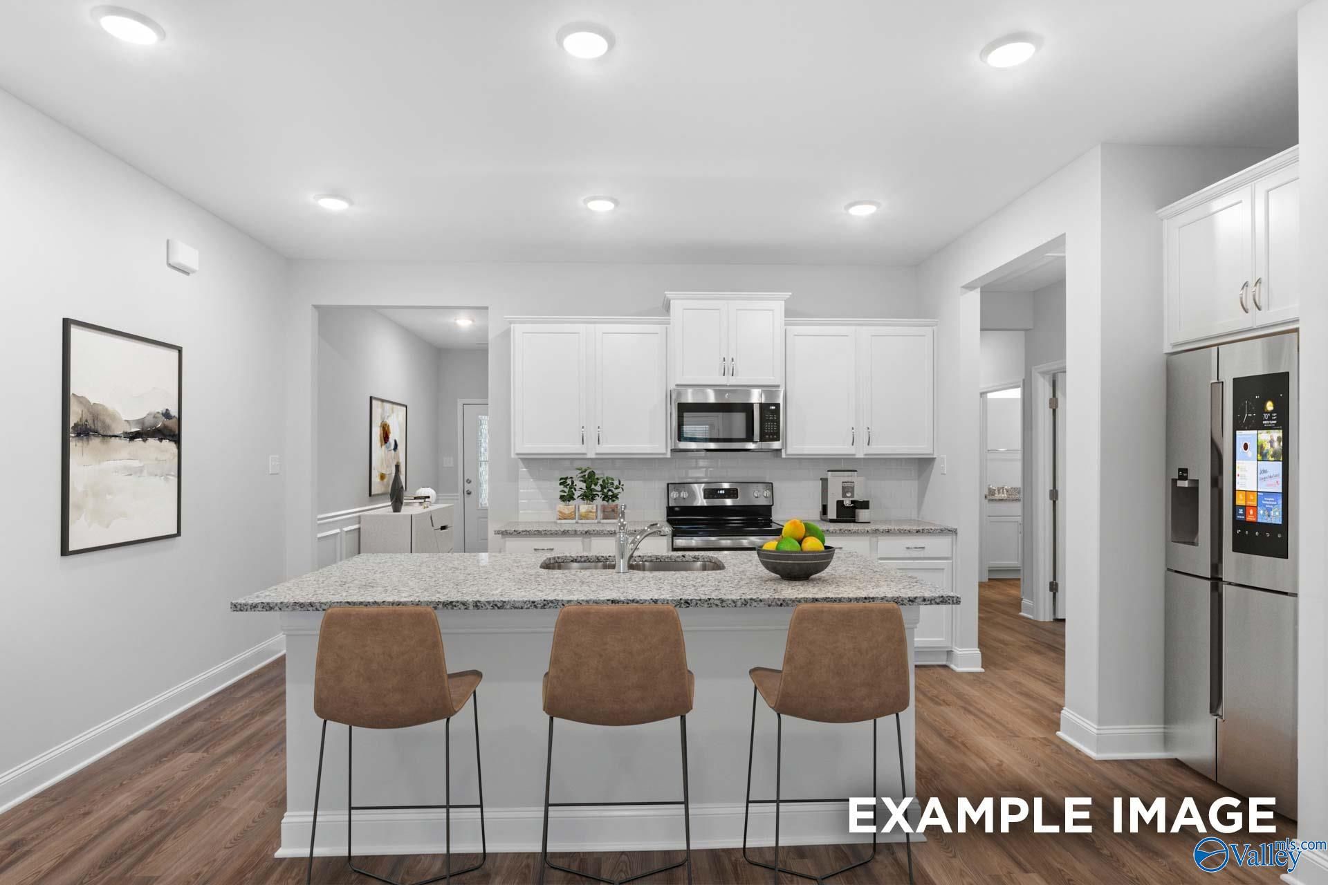 Open-concept kitchen with white cabinets, granite island, stainless appliances, and bar seating in Davidson Homes The Cumberland, Decatur, AL