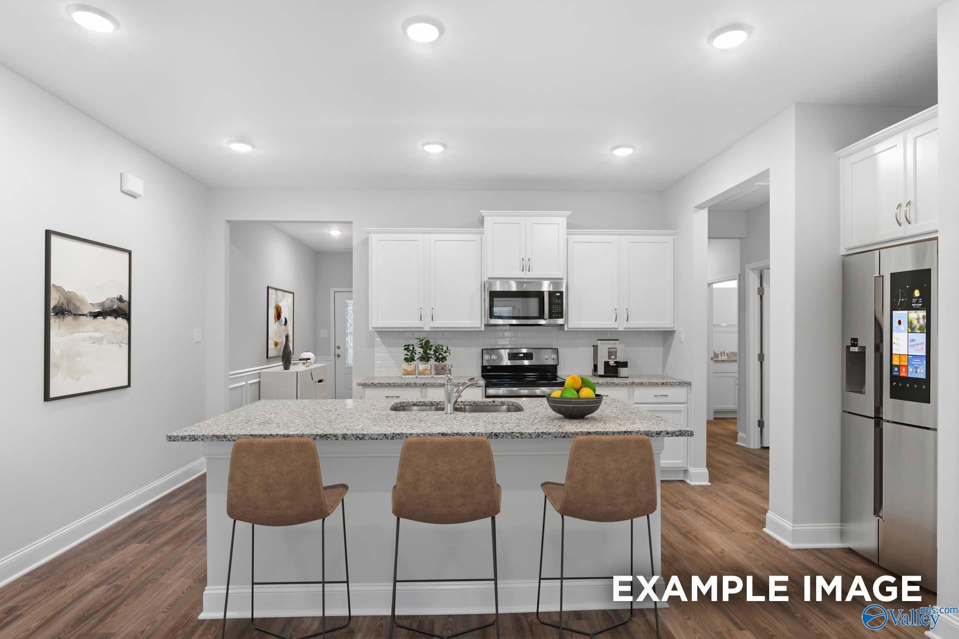 Open-concept kitchen with white cabinets, granite island, stainless appliances in Davidson Homes The Cumberland, Decatur, AL