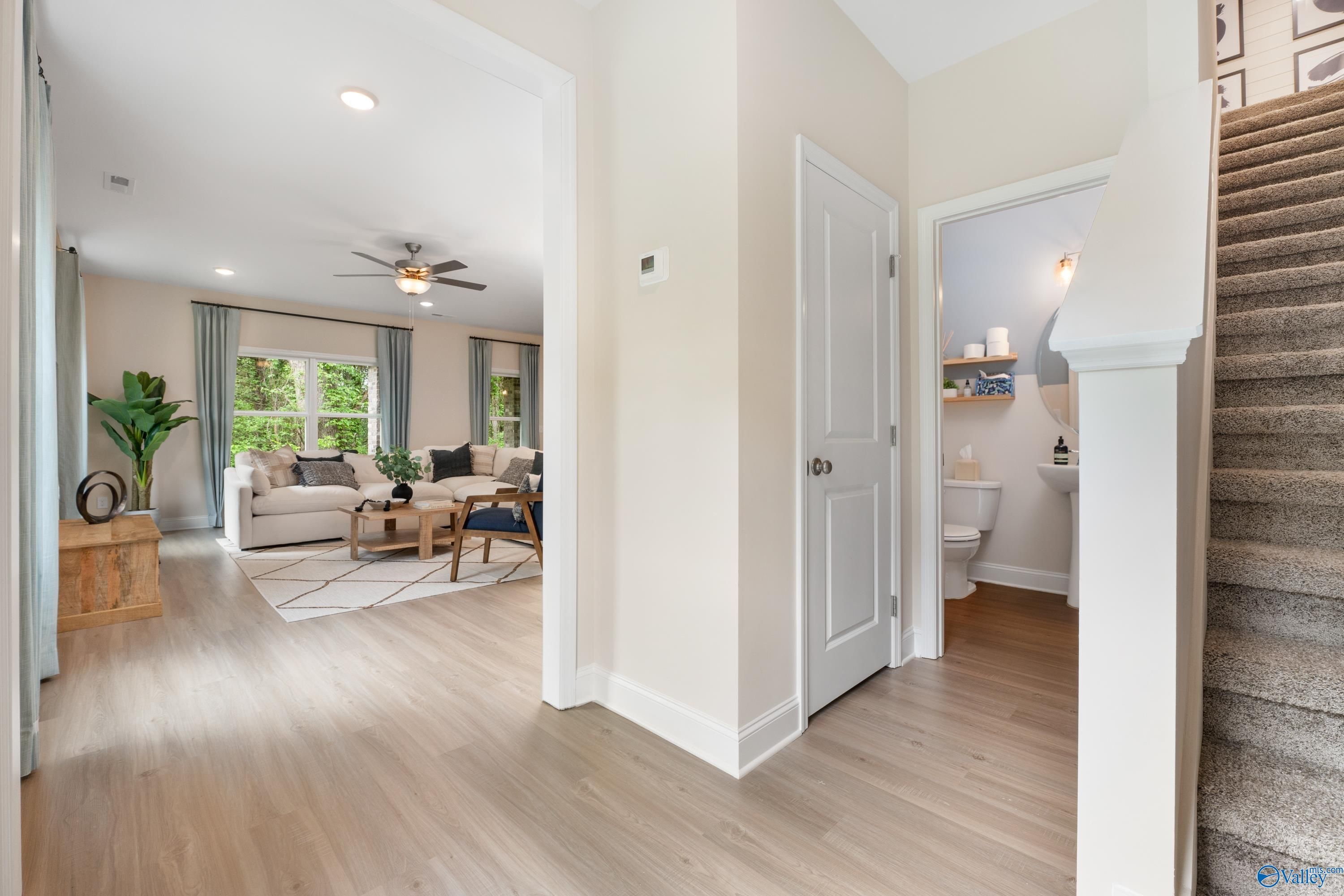 Bright entry foyer with curved staircase, cozy living area, and open powder room in Davidson Homes The Camden, Huntsville AL
