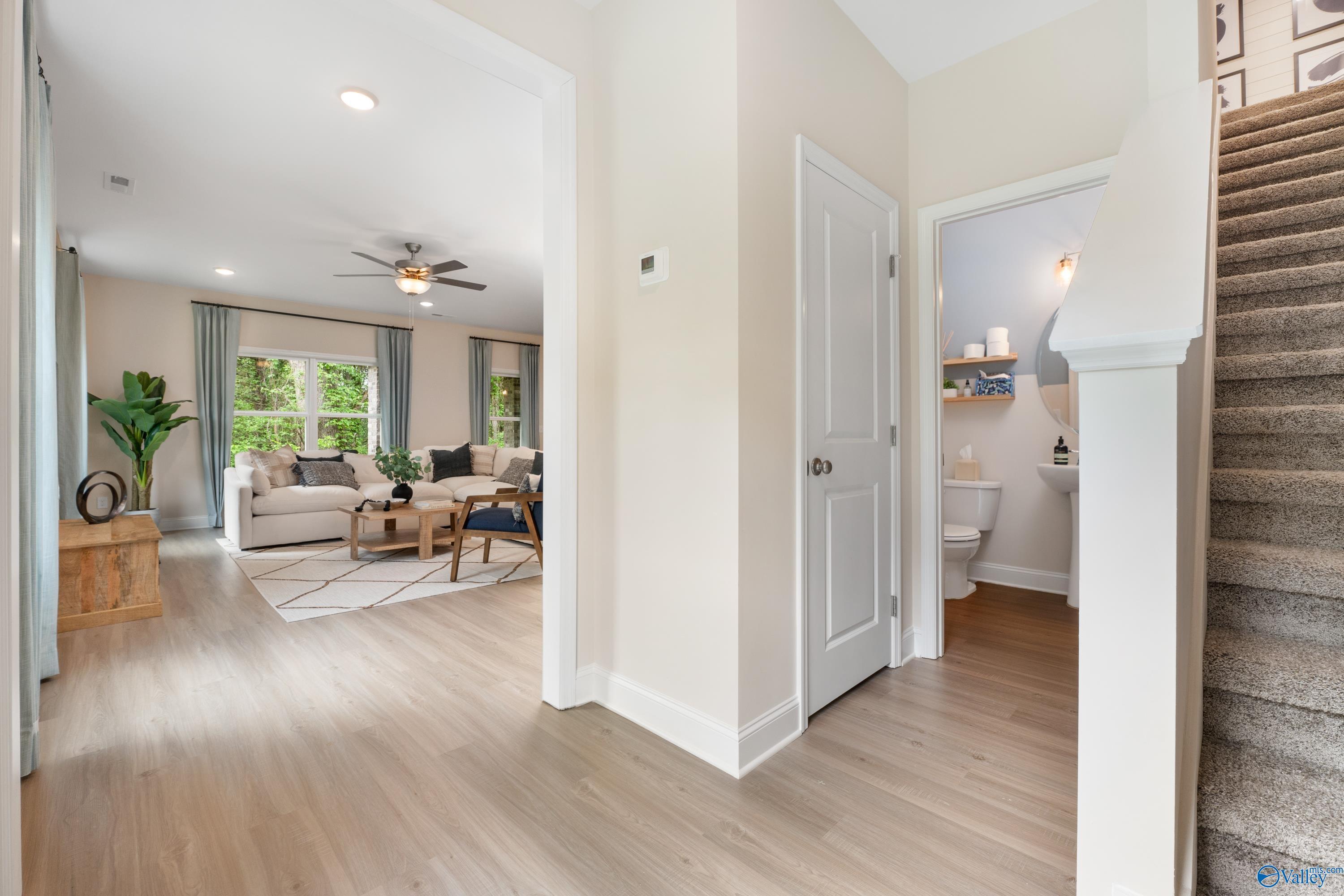 Bright entry foyer with curved staircase, cozy living area, and open powder room in Davidson Homes The Camden, Huntsville AL