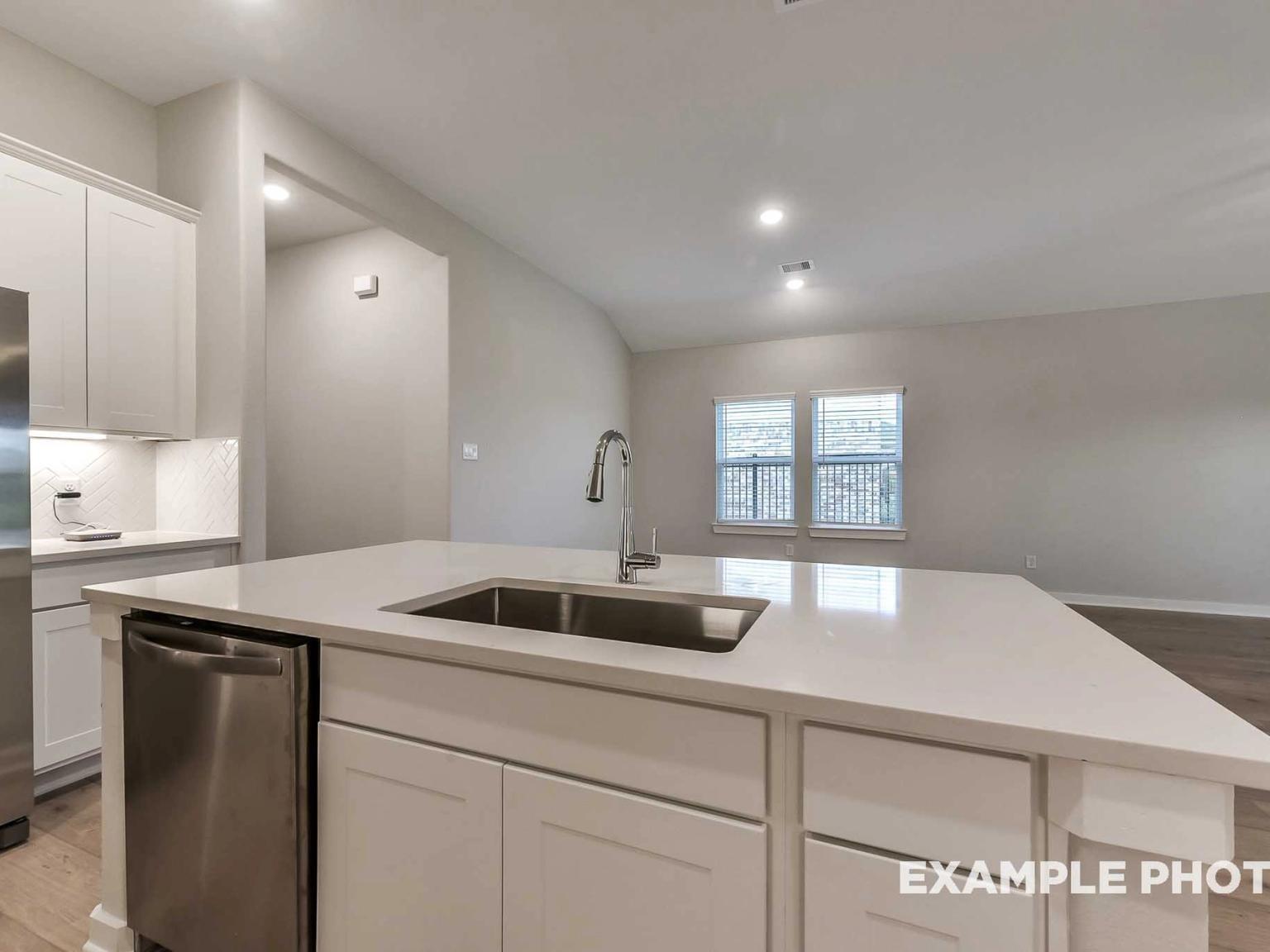 Modern kitchen island with quartz countertops and stainless steel sink in The Brookside F plan at Enclave at Newport, Crosby.