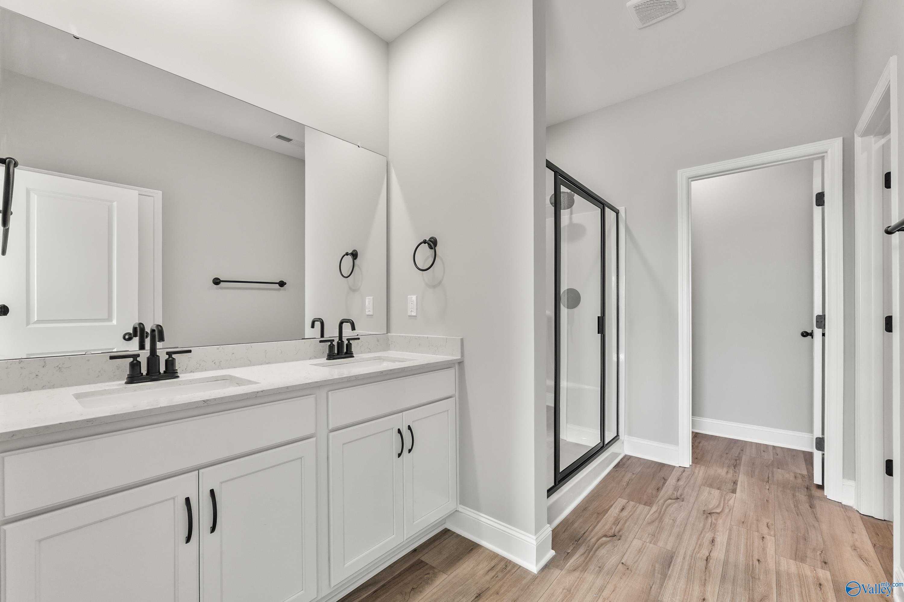Modern master bathroom with double quartz vanity, white cabinets, frameless glass shower in Davidson Homes The Daphne C, Hazel Green, Alabama