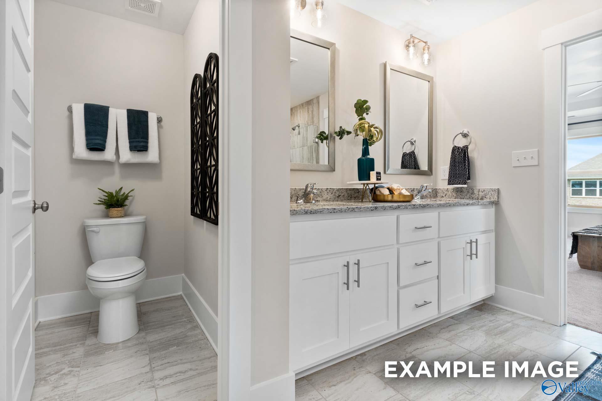 Dual vanity bathroom with granite countertops, white shaker cabinets, and tile floors in Davidson Homes The Chelsea A, Toney, Alabama