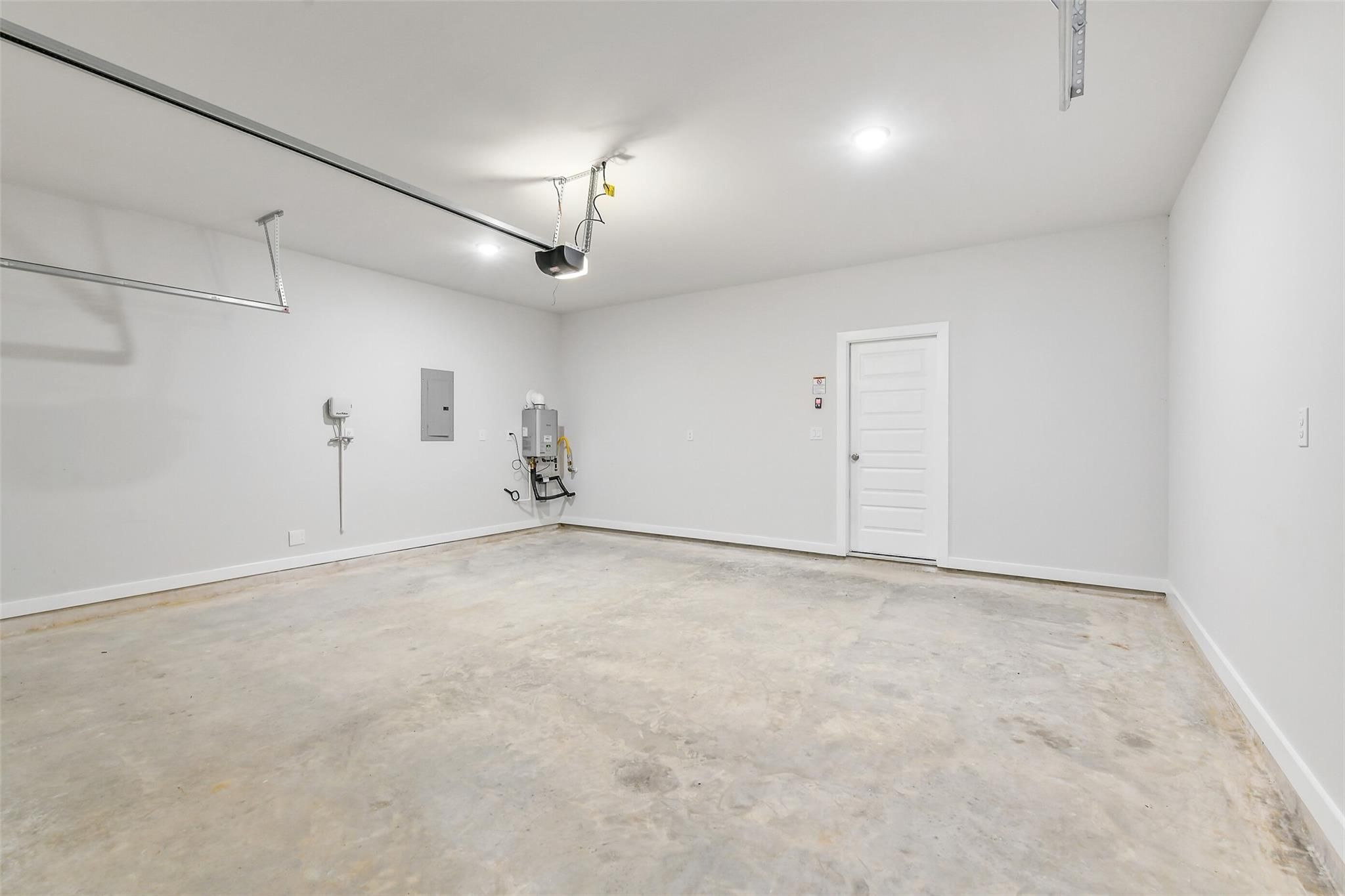 Spacious 2-car garage with concrete floor, white walls, and utility features in Davidson Homes The Blanco E, Magnolia, Texas