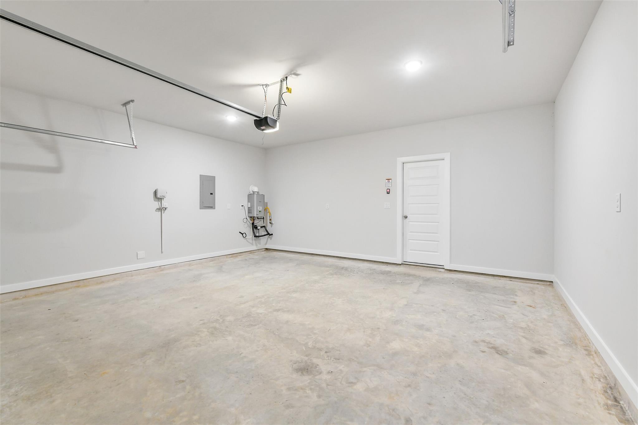 Spacious 2-car garage with concrete floor, white walls, and utility features in Davidson Homes The Blanco E, Magnolia, Texas